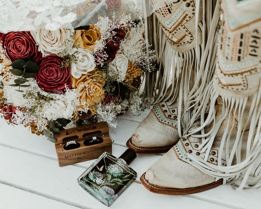 A collection of vintage-inspired wedding decor with dried roses, macrame, and rustic wooden elements arranged on a white surface.