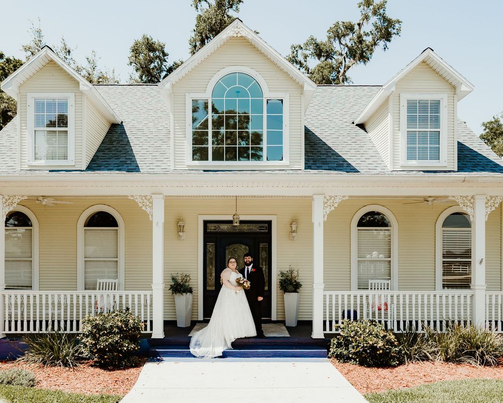 A panoramic view of a white colonial style house with multiple windows and arched entryway details.