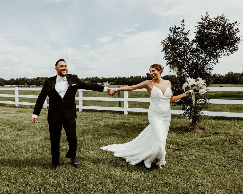 A playful wedding sequence shows a couple spinning and twirling gracefully in a grassy field with white fences in the background.
