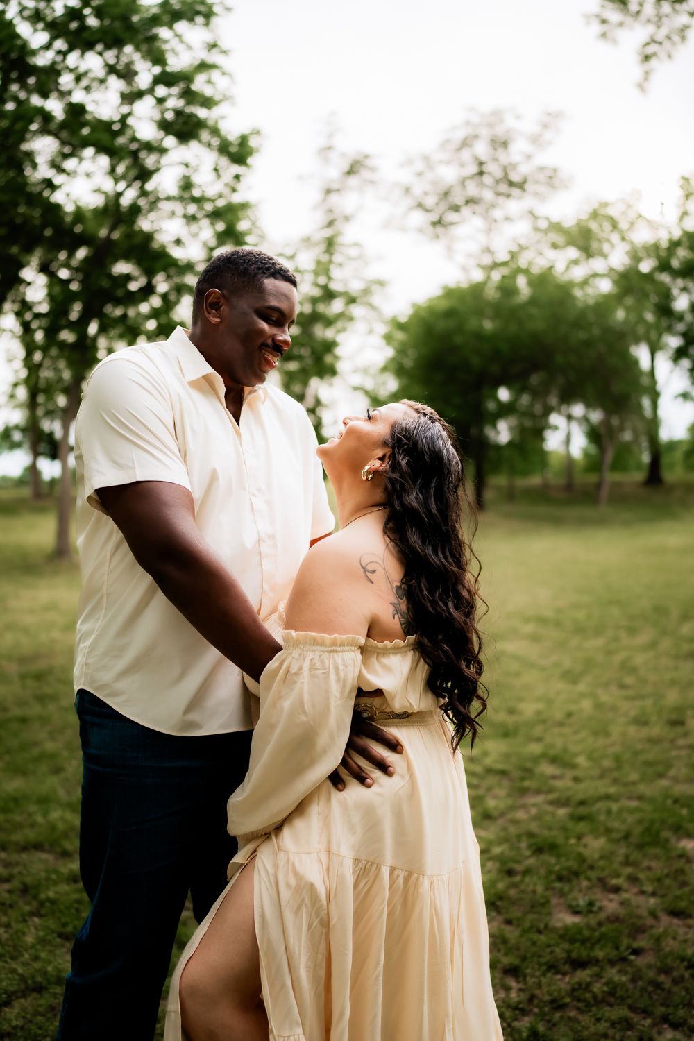 A loving couple shares a joyful moment together outdoors in coordinated cream colored outfits.