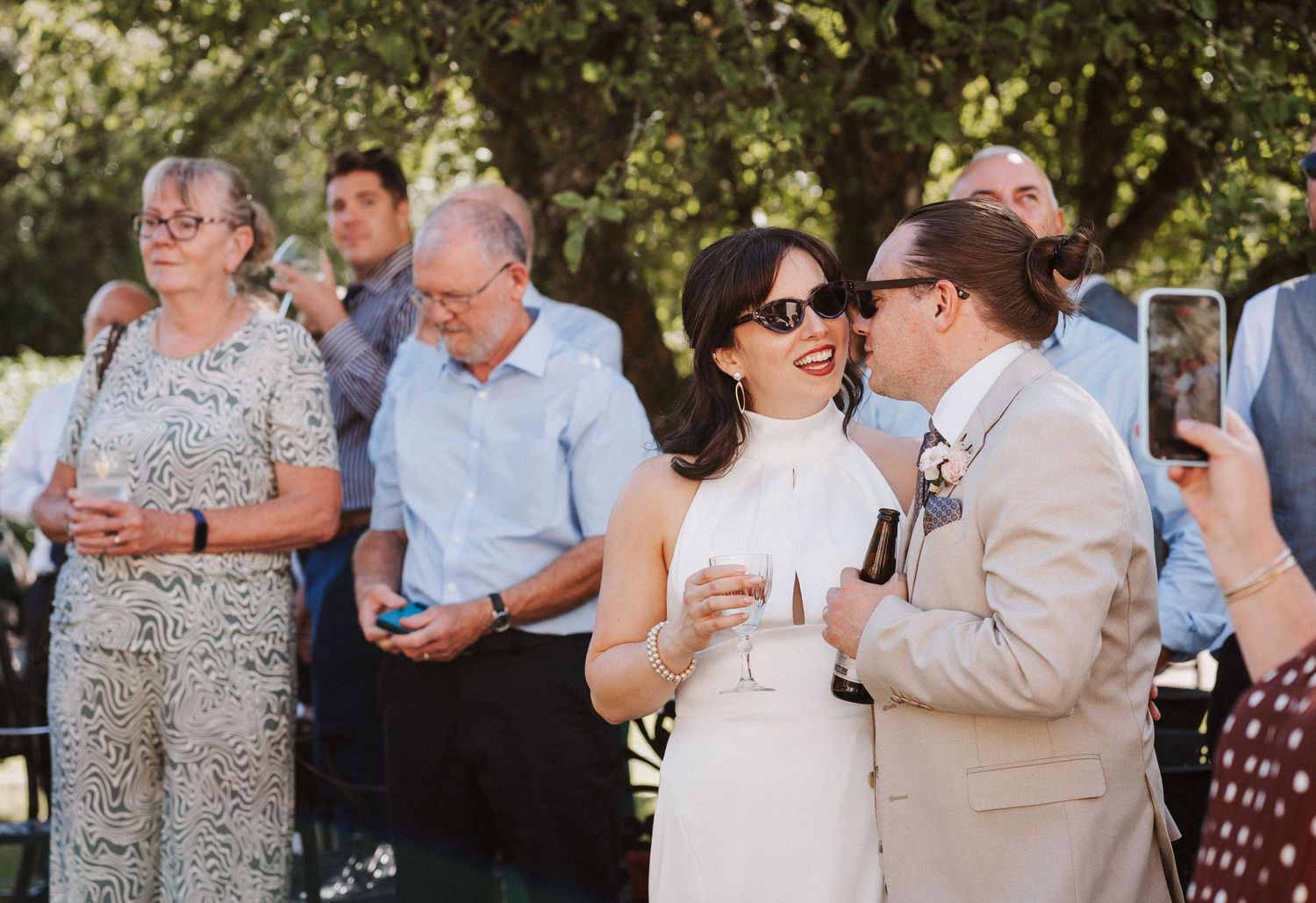 Group of guests enjoying conversations and socializing during an outdoor daytime celebration event.