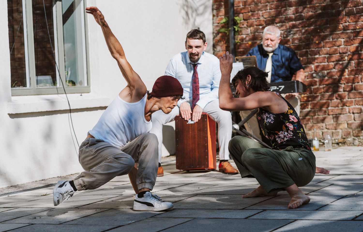 A person in jeans and white shirt performs parkour moves beside a brick wall in an urban setting.