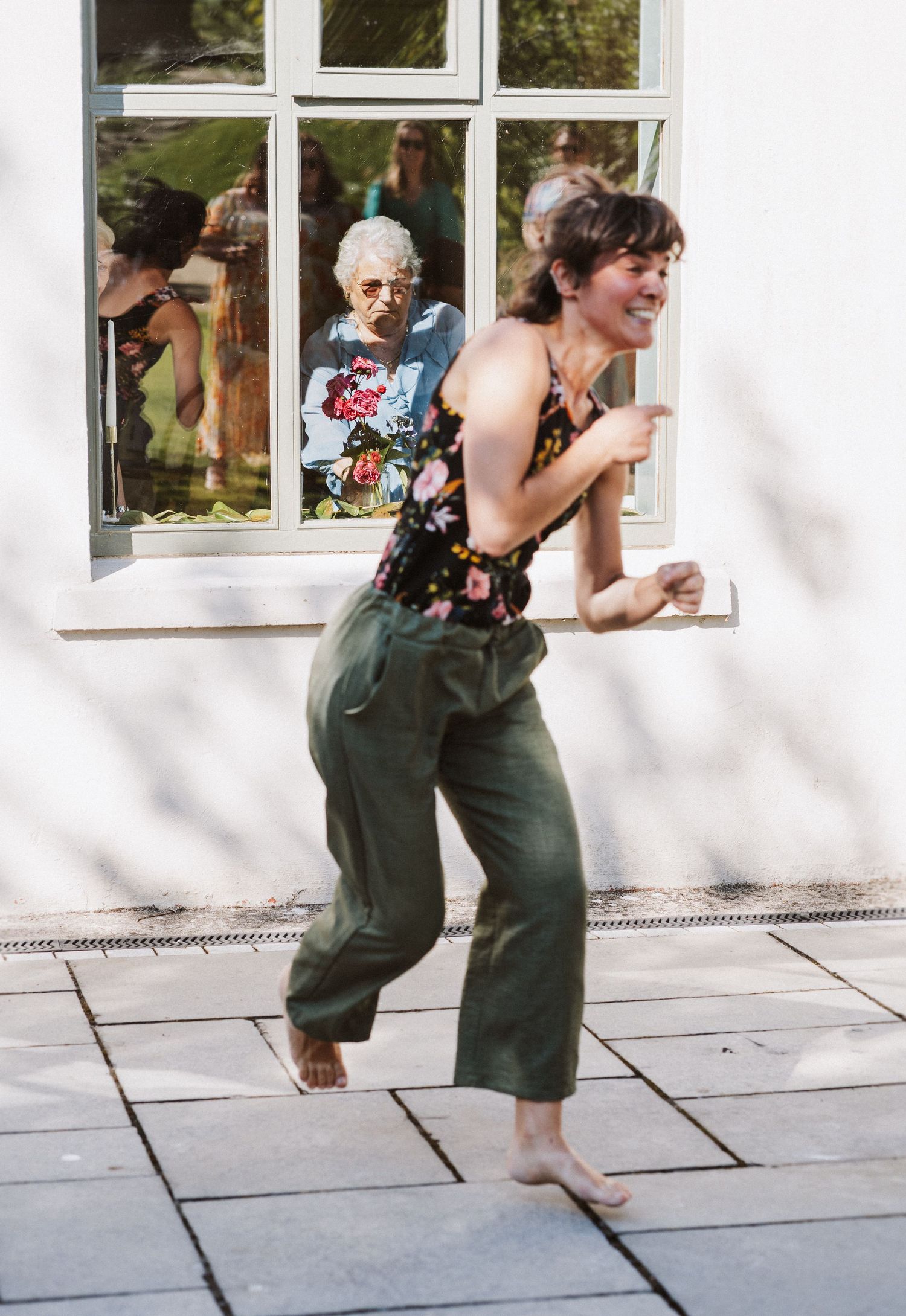 Sequence of four photos showing someone in green overalls bending down to look through white-framed windows.