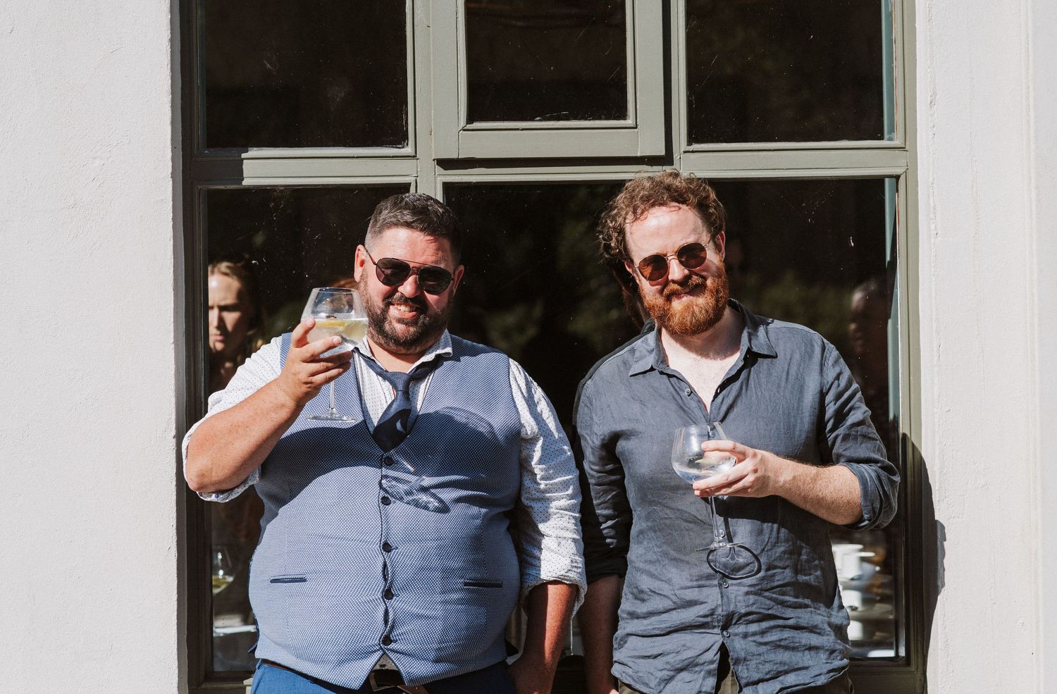 Five people in matching gray button-down shirts stand together outside a building with windows.