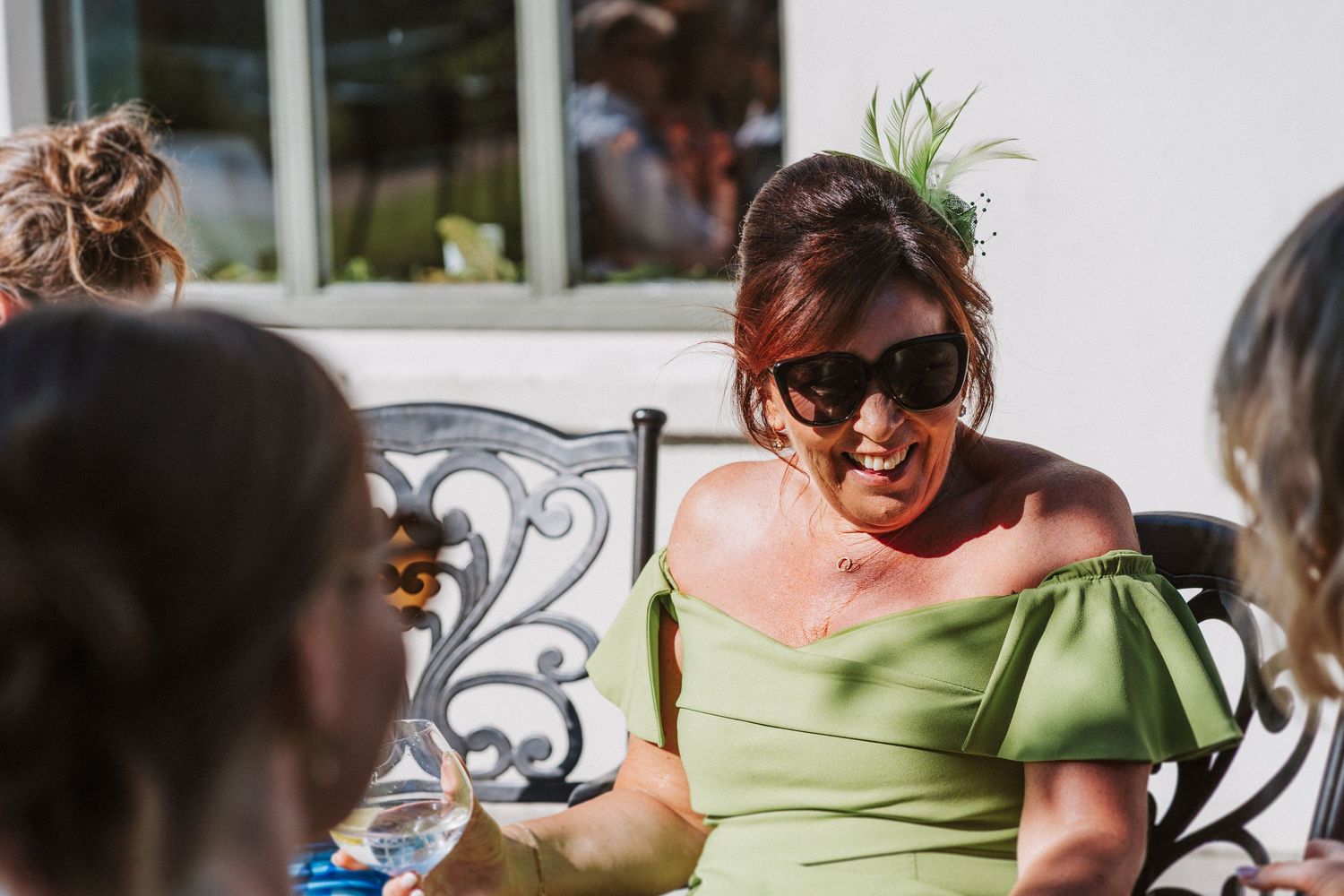 Group of people enjoying outdoor dining and conversation at a sunny patio table setting.