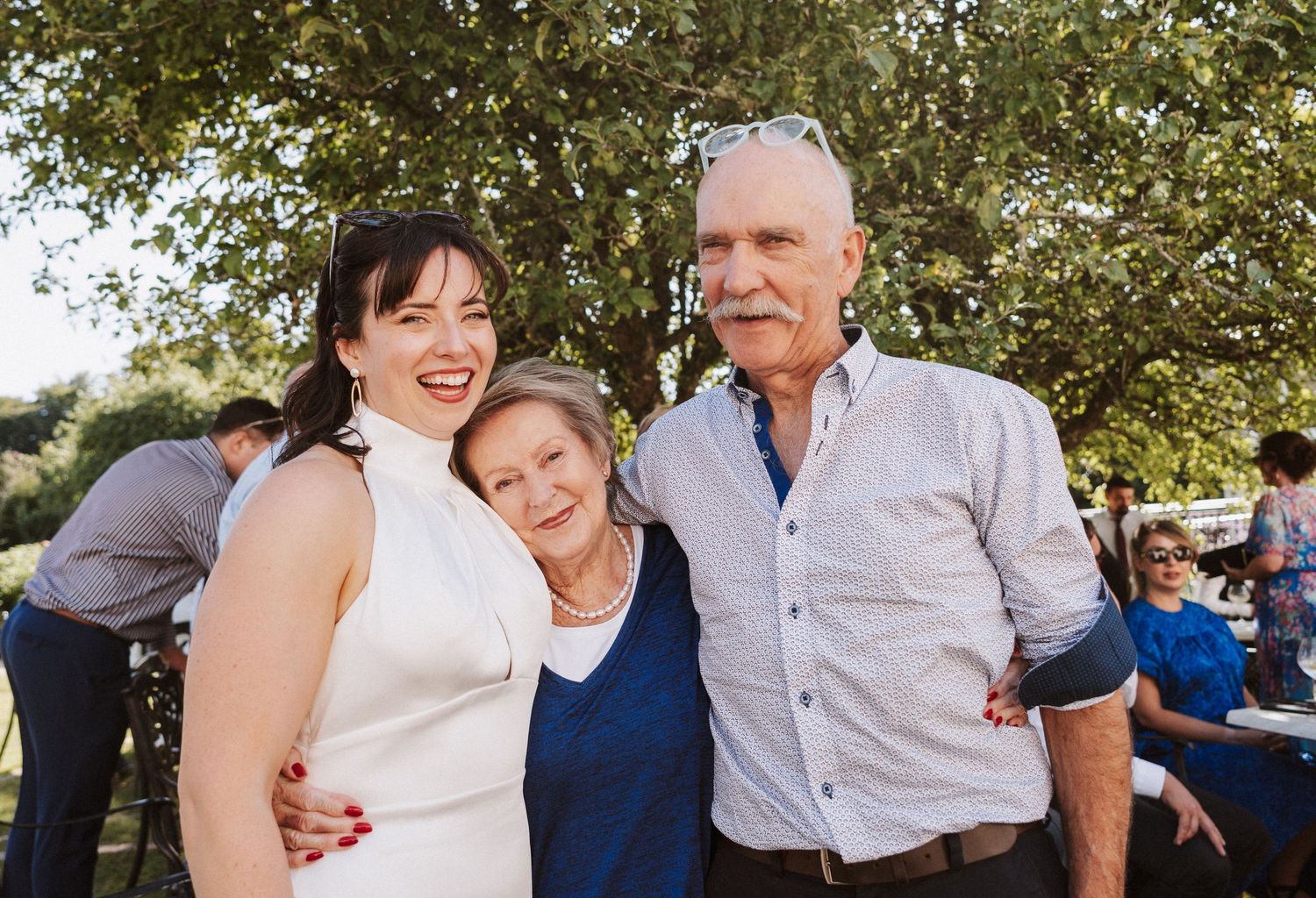 Joyful gathering of people celebrating at an outdoor event with trees in the background.