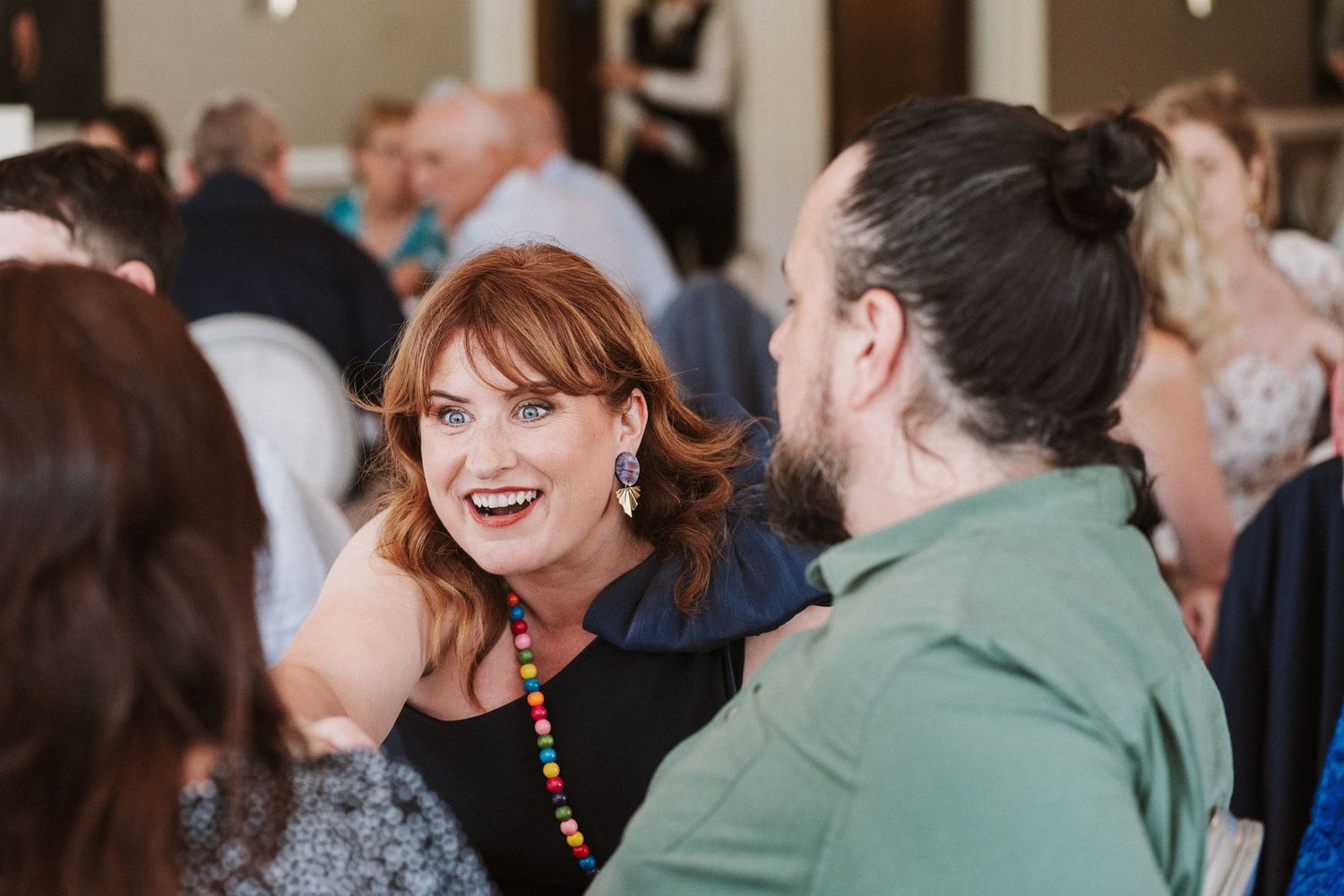 People gathered in a social setting engaging in lively conversation and interaction at an indoor event.