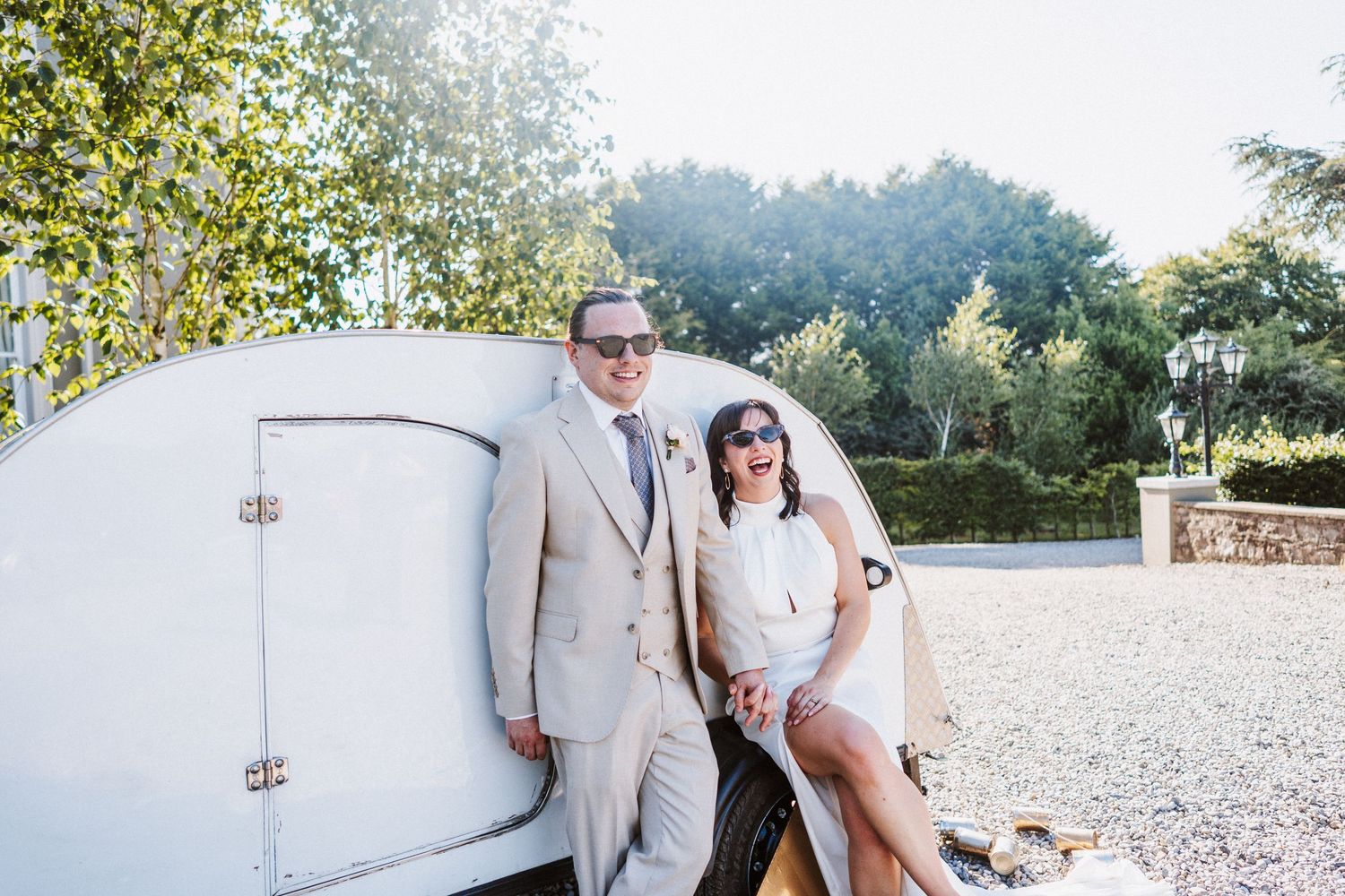 Wedding couple poses together in a rustic outdoor setting with trees and natural light in the background.