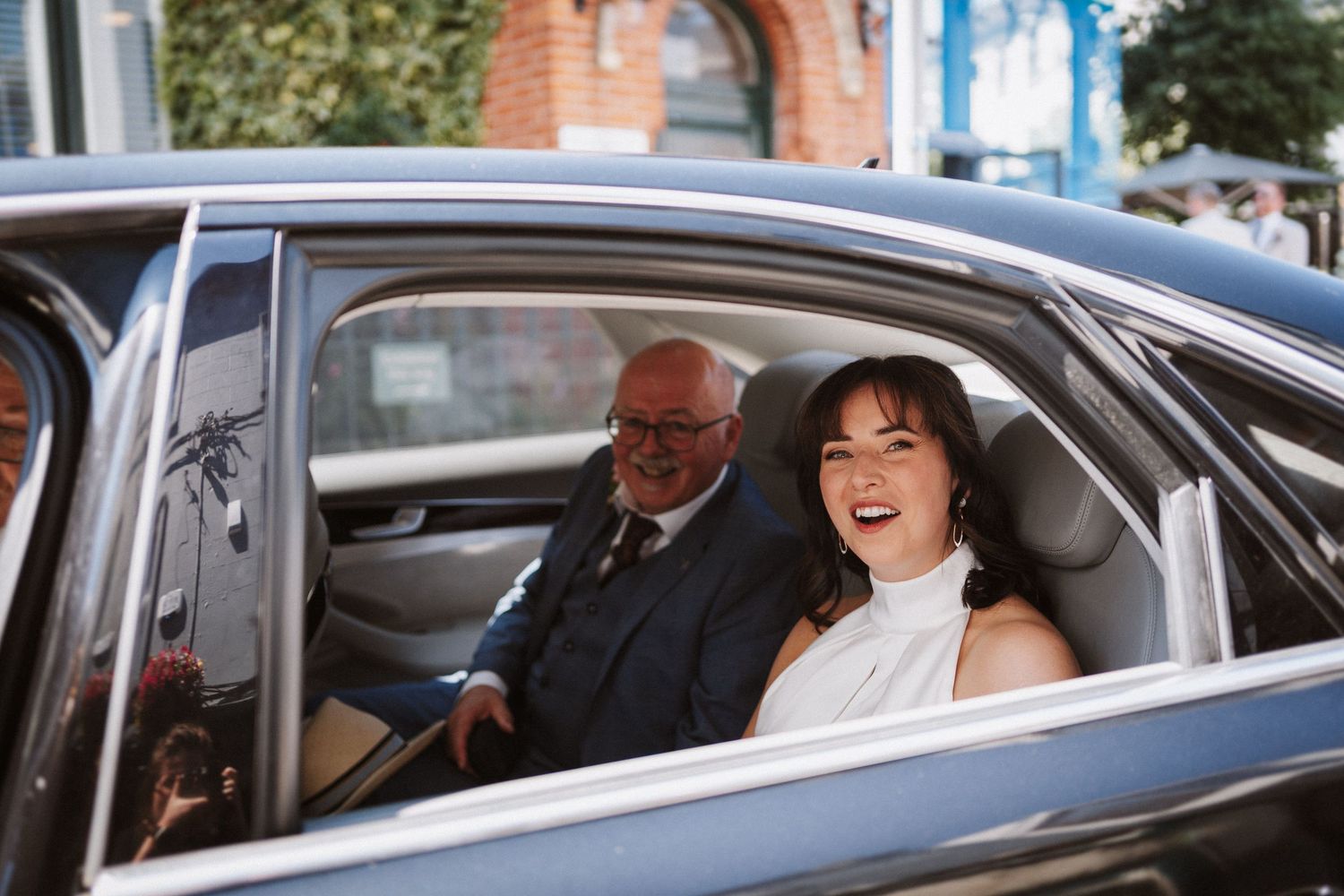 People celebrating and laughing inside cars during a wedding party procession event.