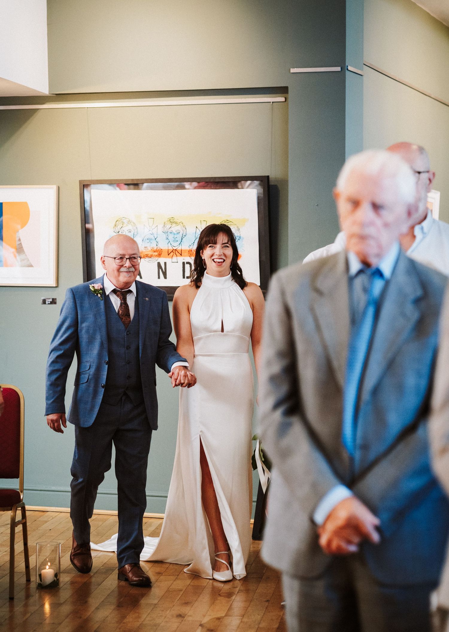 Gallery hallway with a white dress and men in gray suits creating artistic motion blur.