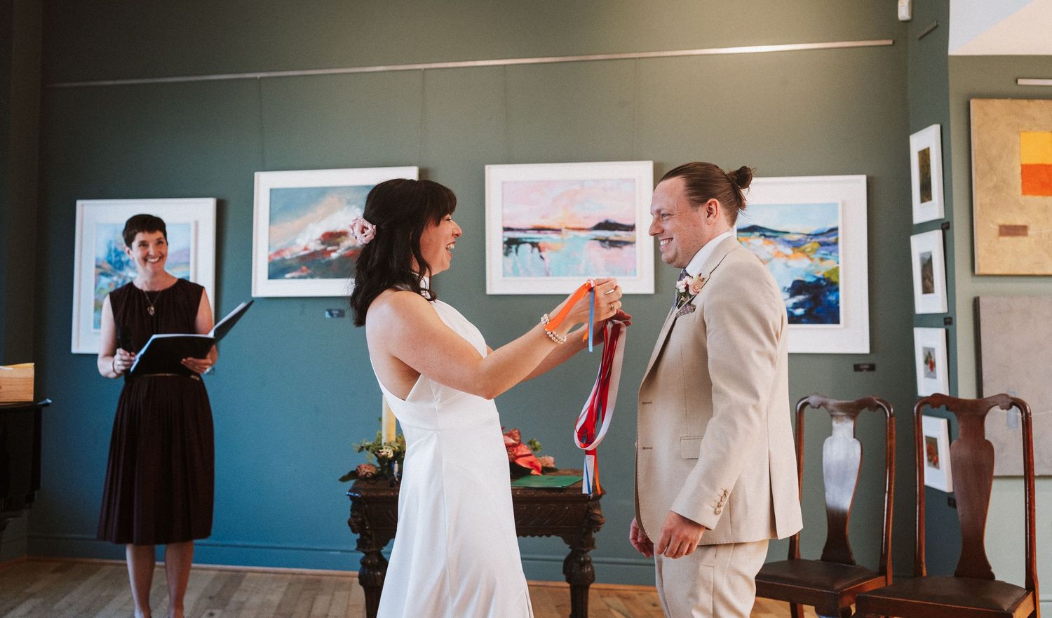 Wedding celebration inside an art gallery with blue walls and framed photographs.