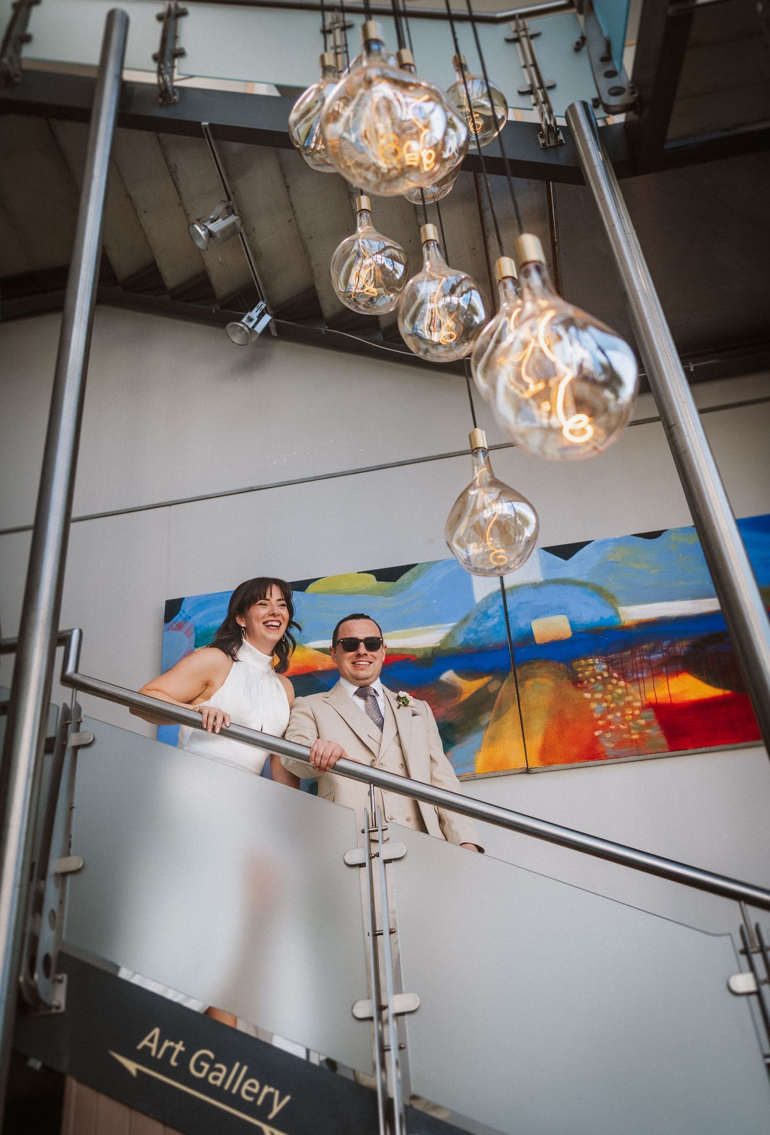 Modern art gallery interior with hanging glass pendant lights and colorful wall mural in the background.