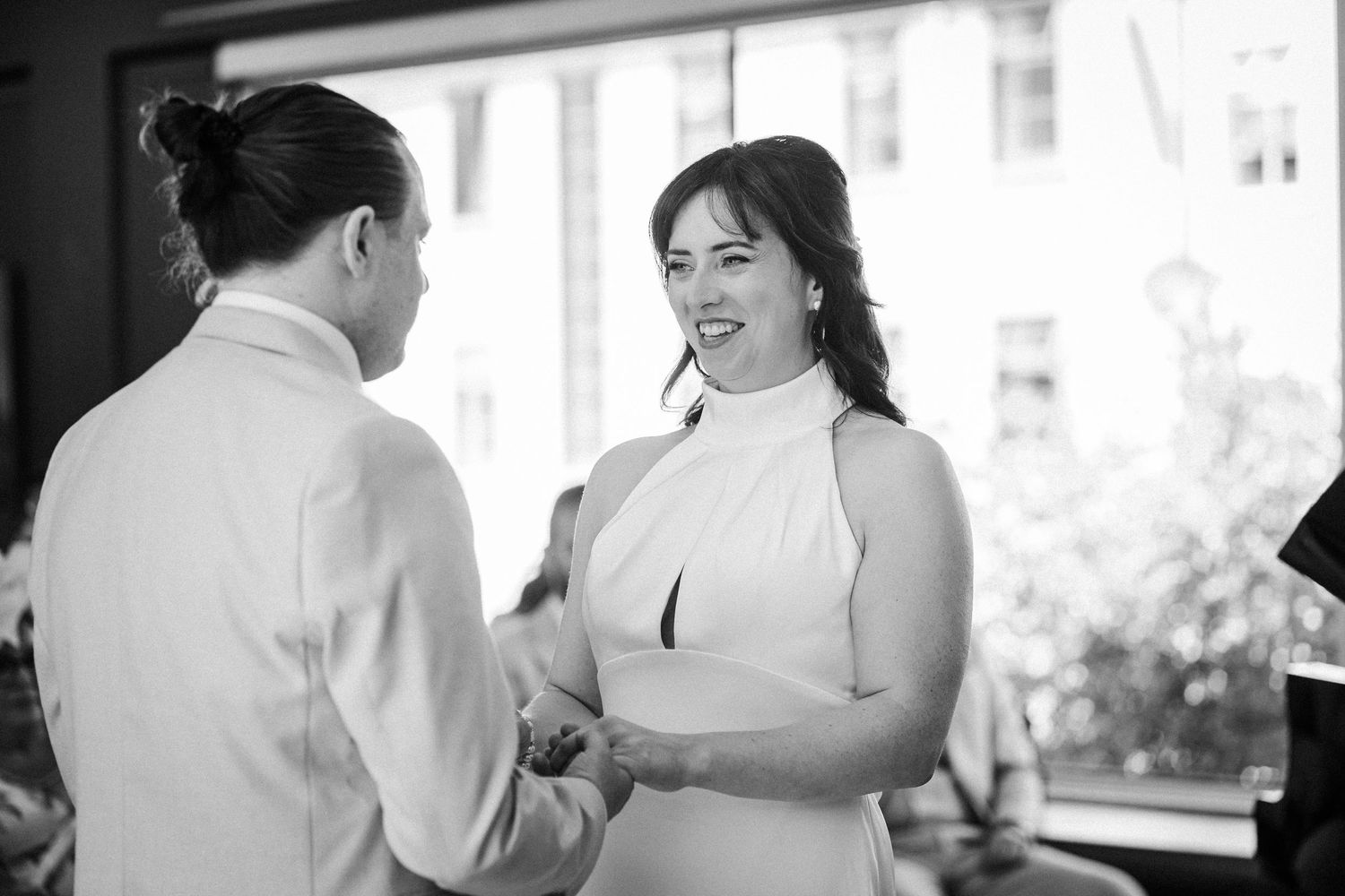 Wedding couple dances together in an elegant indoor setting with natural window light.