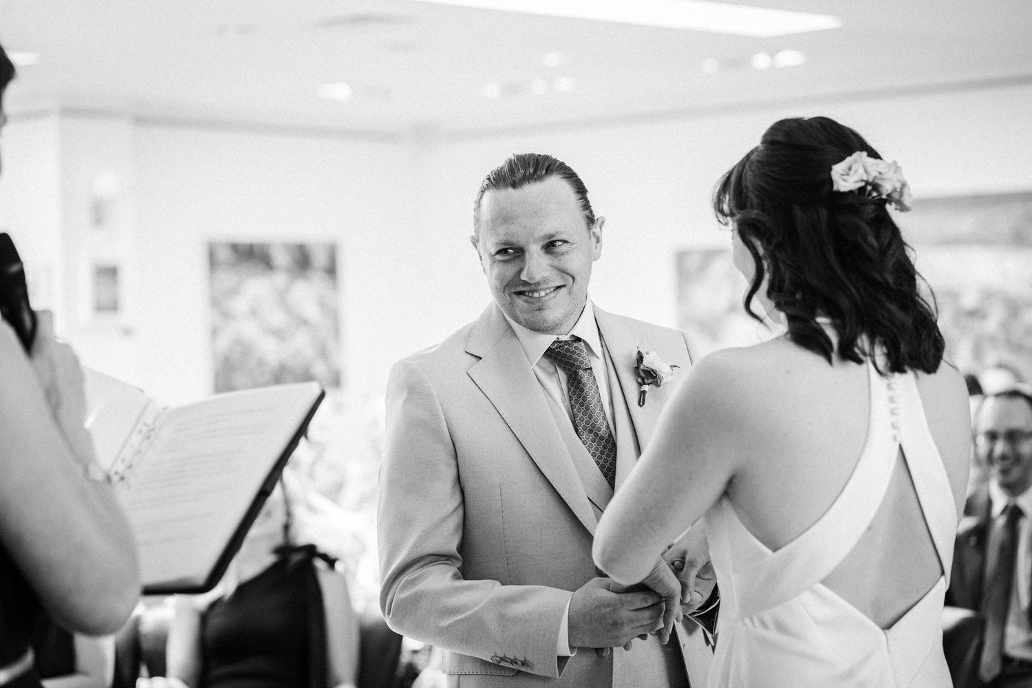 A candid black and white moment during a wedding ceremony showing participants exchanging vows.