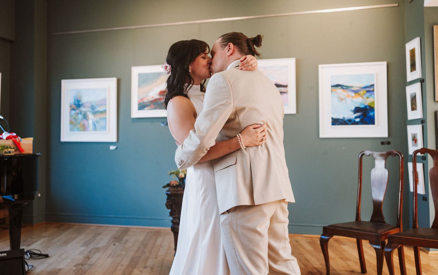 Intimate moments shared between wedding guests in an art gallery with teal walls.