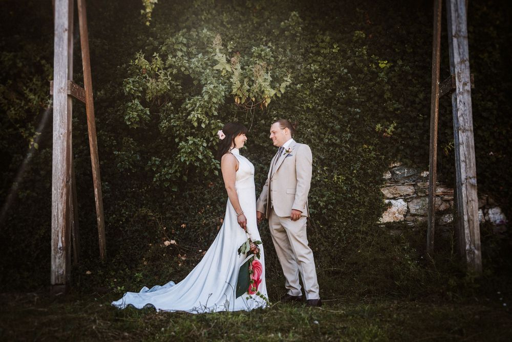 Wedding couple shares intimate moments in a serene wooded setting surrounded by tall trees and natural light.
