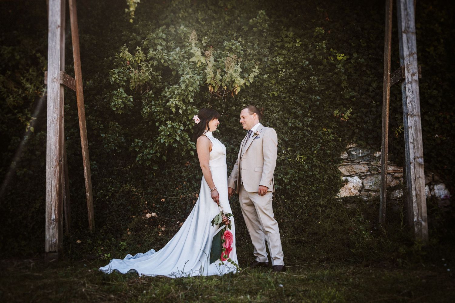 Wedding couple shares intimate moments in a serene wooded setting surrounded by tall trees and natural light.