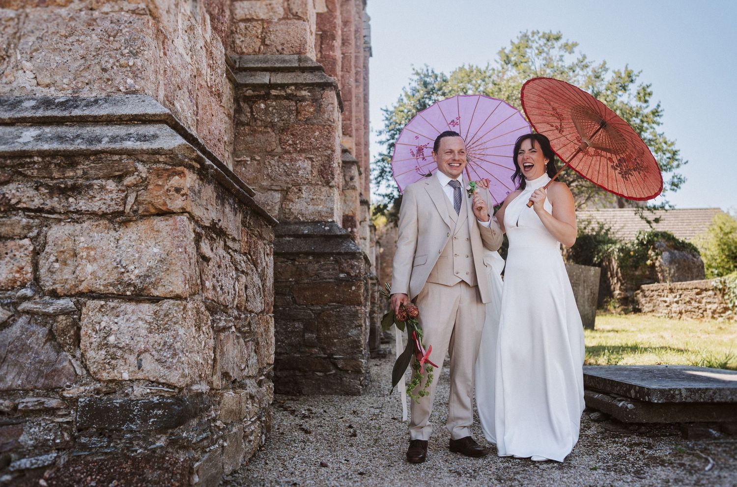 A wedding couple poses in front of historic stone ruins and archways in a romantic outdoor setting.