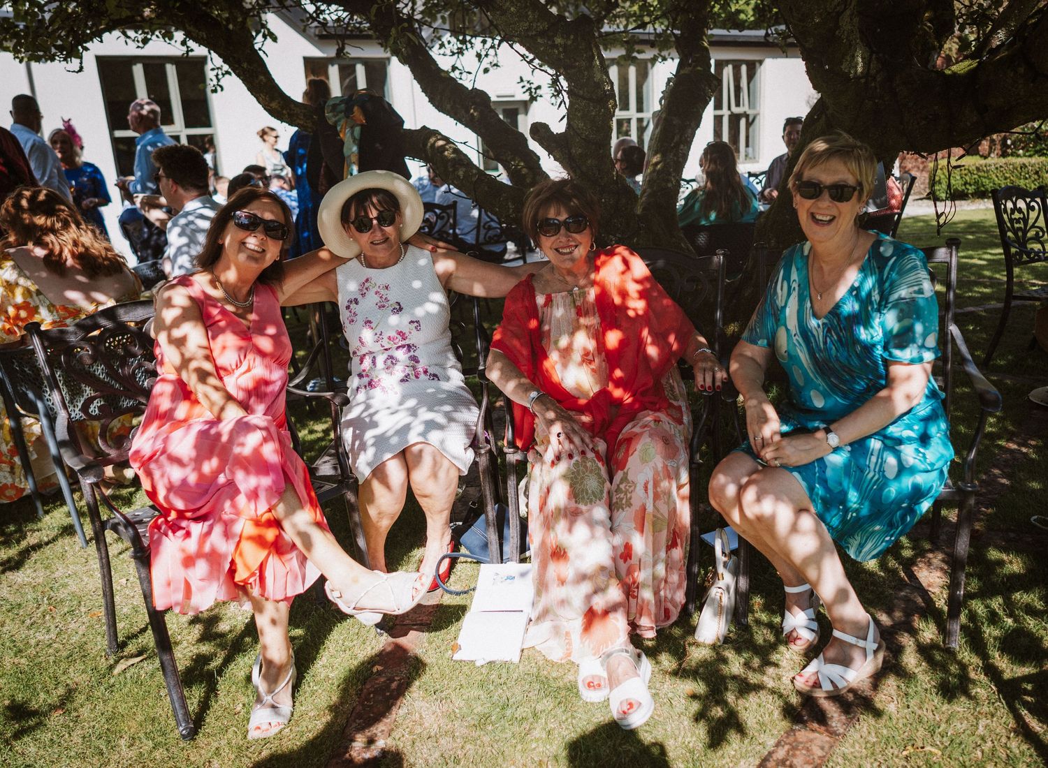 Group sitting together and enjoying a sunny outdoor gathering in a garden setting.