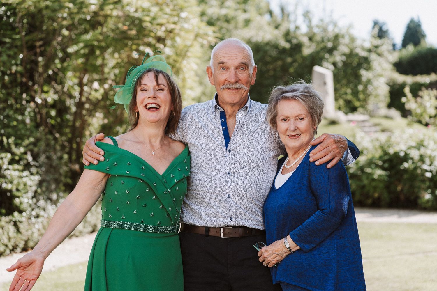 Candid outdoor portrait of people in colorful outfits laughing and smiling together in a garden.
