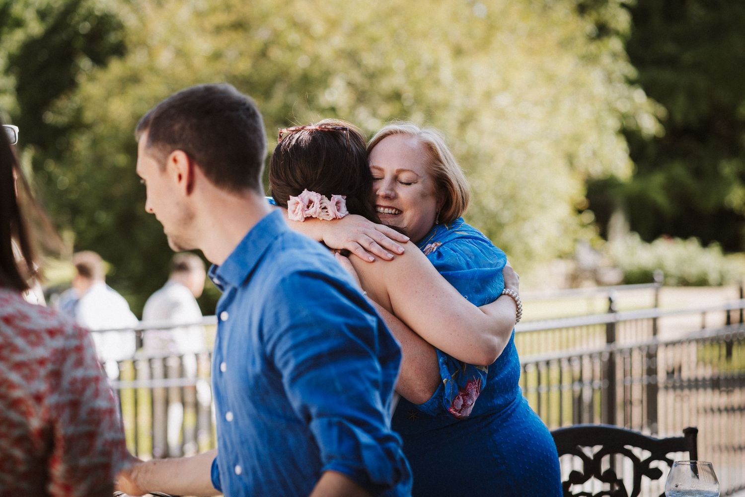 A couple shares a tender embrace while wearing matching blue outfits outdoors with a soft, natural background.