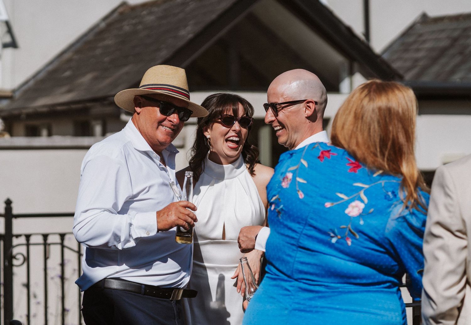 Wedding party wearing blue and white outfits shares a joyful moment on an outdoor patio.