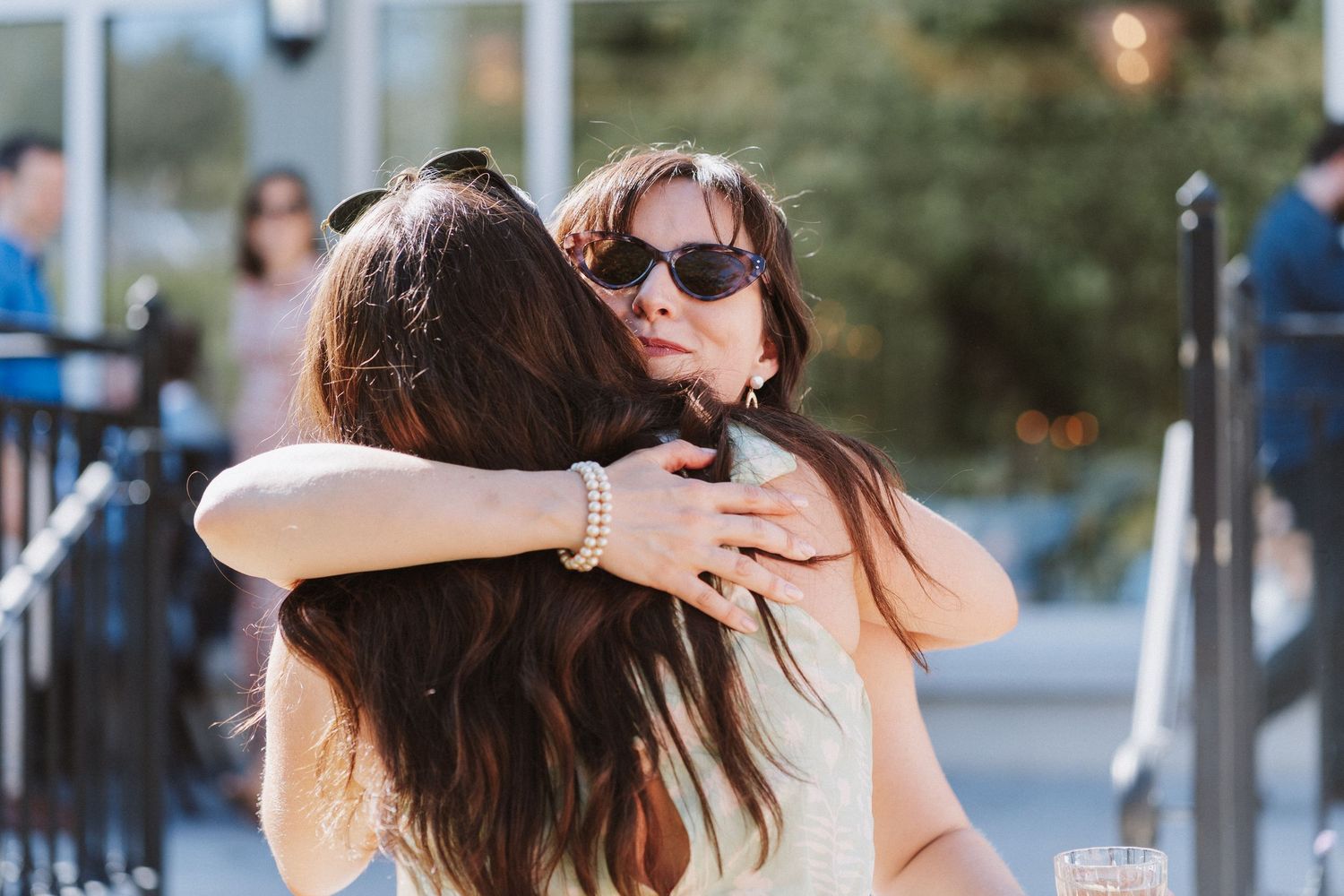 Best friends wearing sunglasses laugh and smile together on a sunny summer day in the city.
