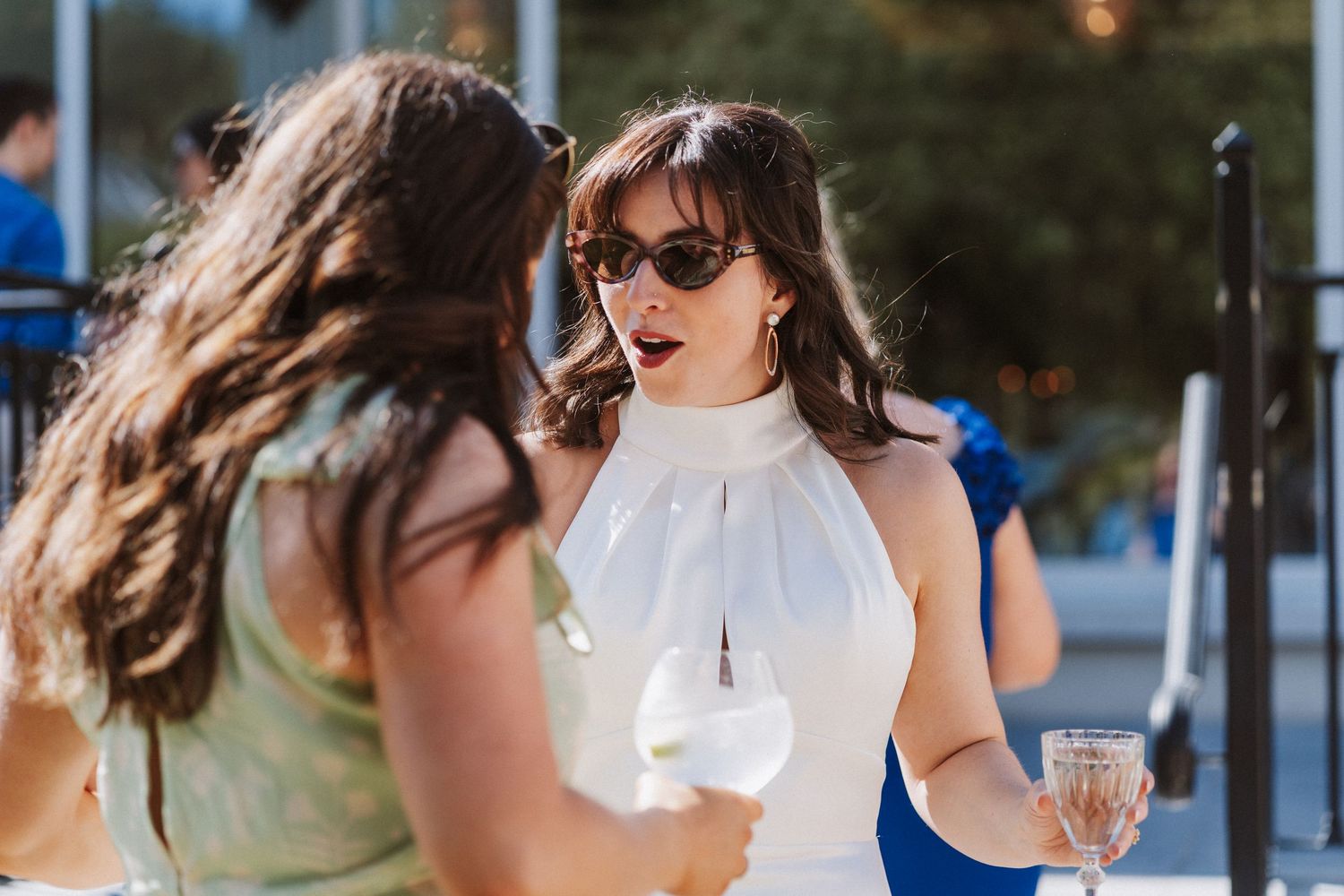 Three women in sunglasses share joyful moments while walking outdoors.