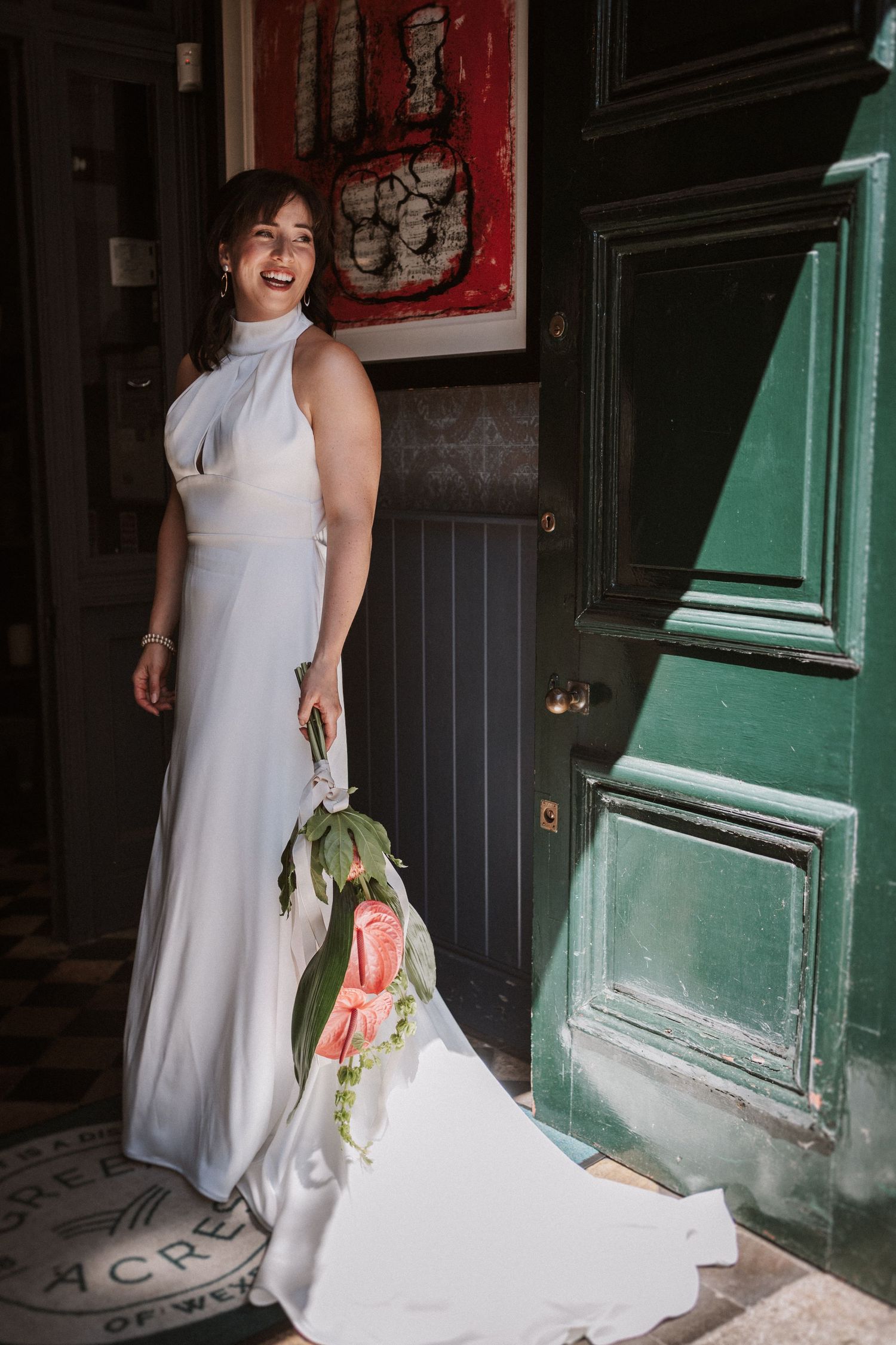 A white wedding dress trails on the ground near a mint green doorway in an artistic composition.