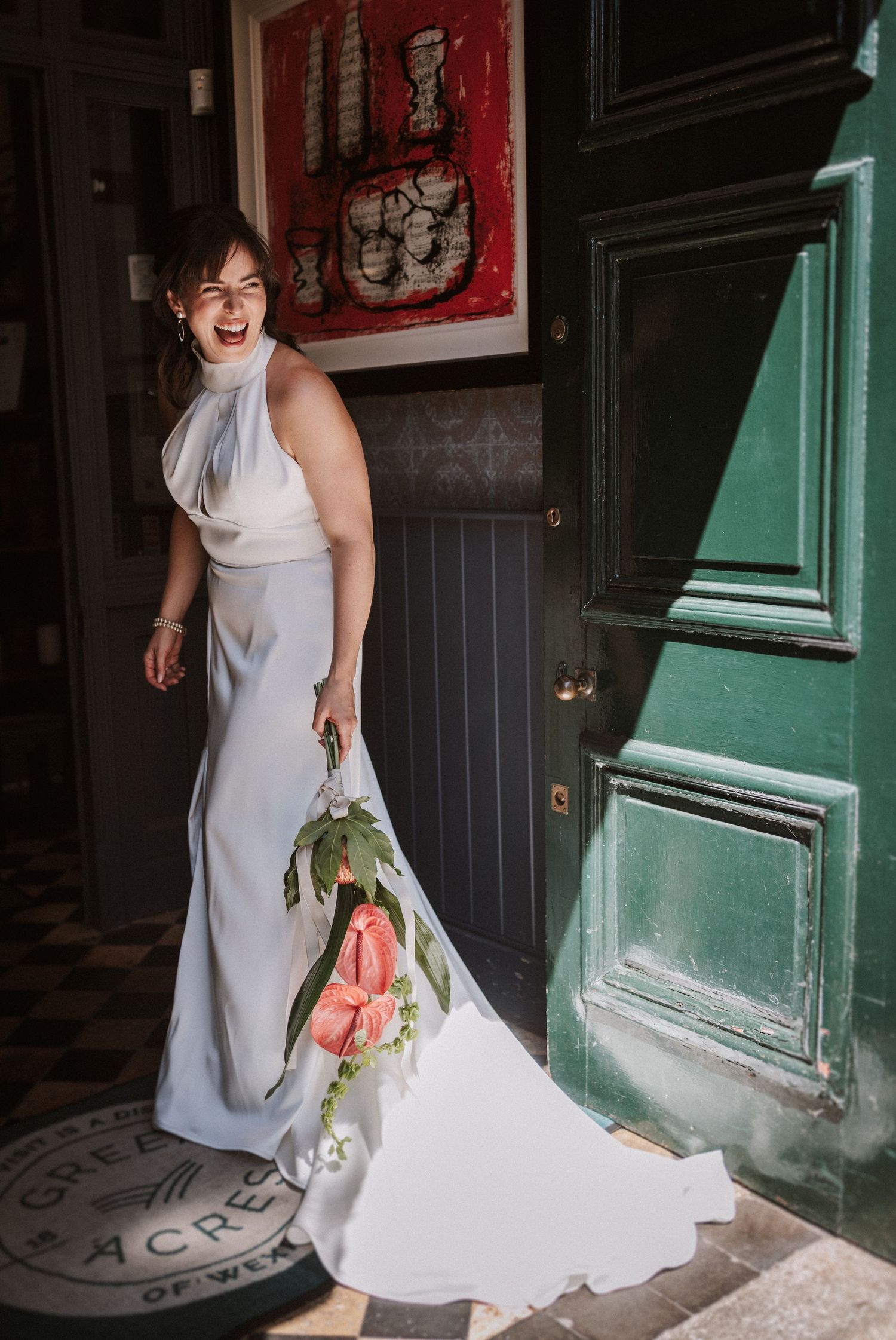 A white dress flows across a green doorway in a creative wedding photo composition.