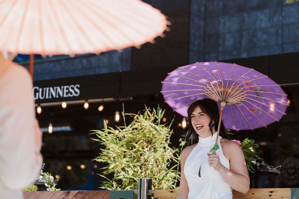 A colorful scene with pink and purple paper parasols against a dark background with a Guinness sign visible.
