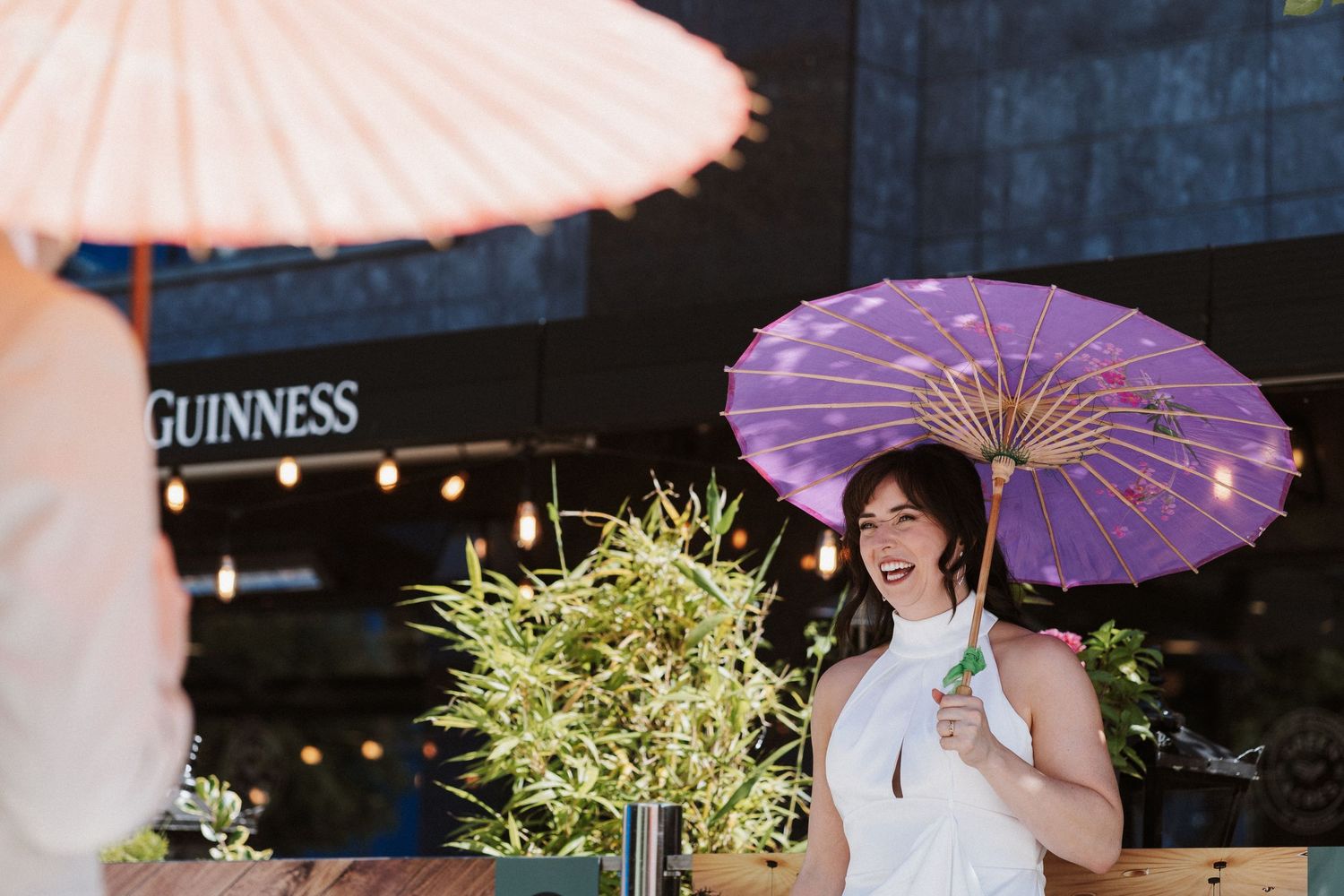 A colorful scene with pink and purple paper parasols against a dark background with a Guinness sign visible.