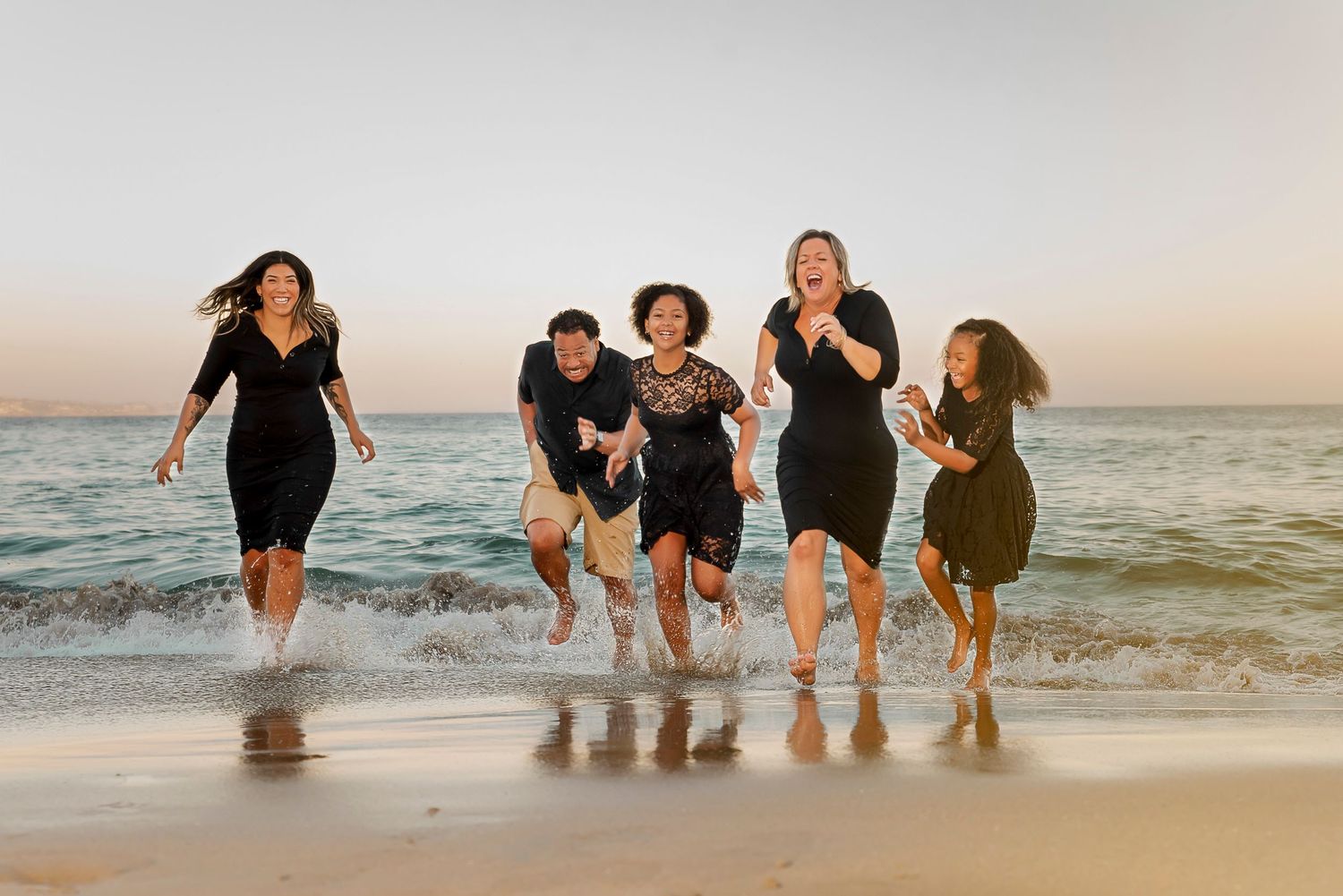 Group of friends playing and splashing together in ocean waters at sunset.