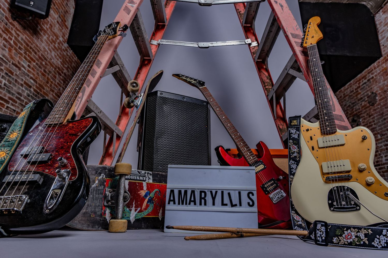 Musical instruments and equipment arranged in studio setting with brick wall backdrop.