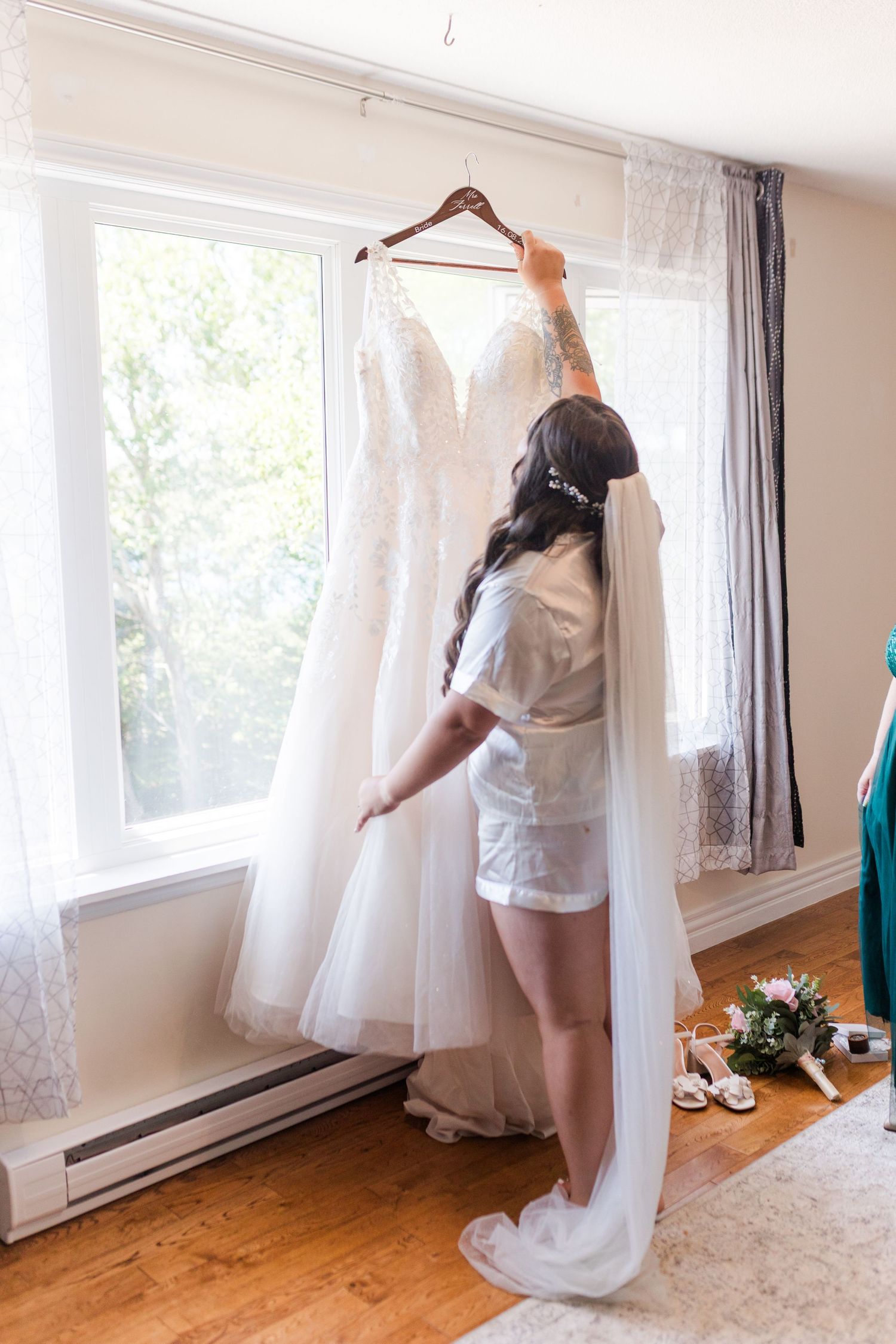 A sequence showing someone hanging white curtains on large windows in a room with hardwood floors and natural lighting.