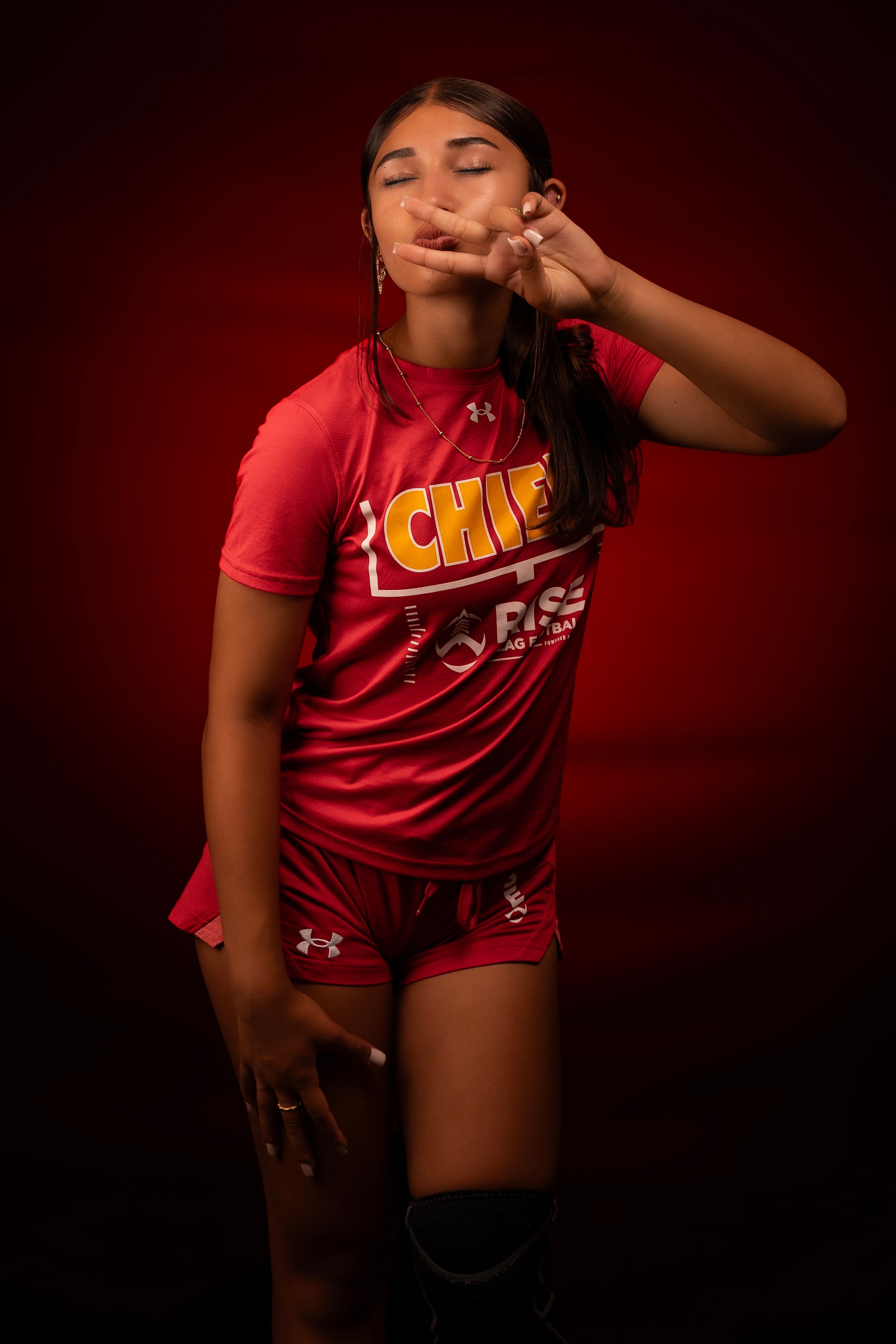 Athletic portrait against deep red backdrop showing red jersey with gold Chiefs lettering.