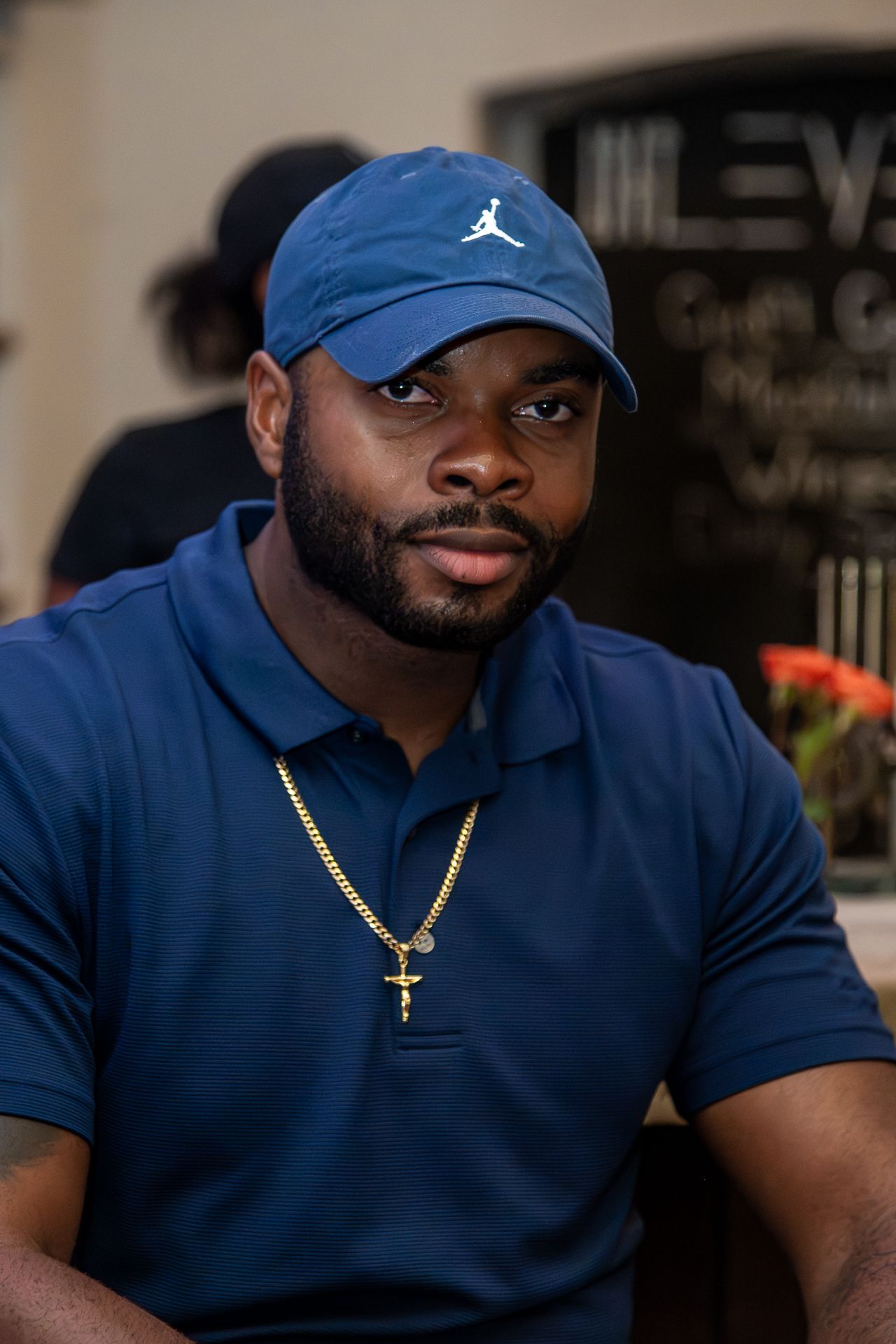 Series of photos showing person wearing navy blue polo shirt and Jordan cap with gold chain accessory in dim lighting.