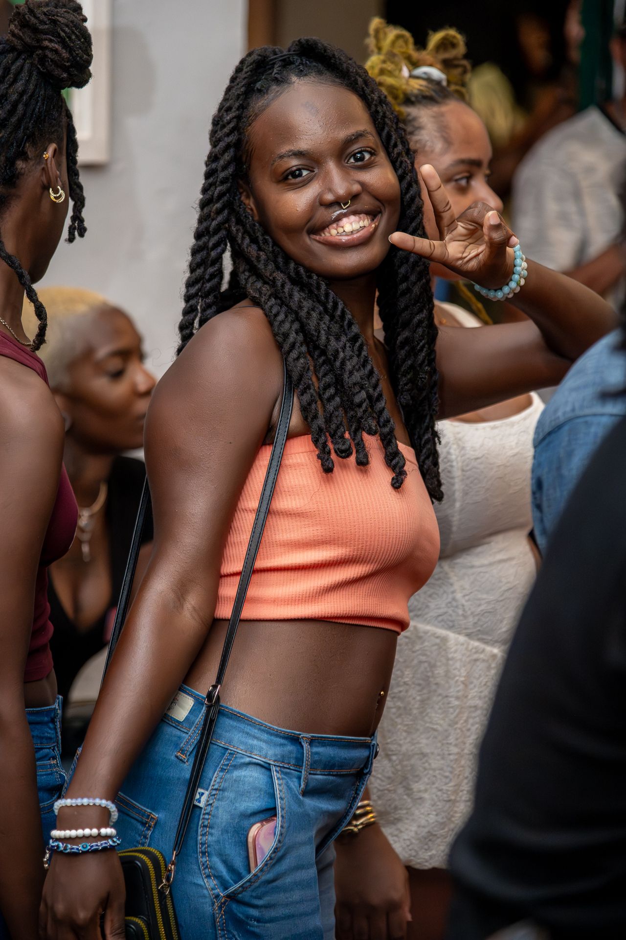 Several people posing and smiling while wearing casual outfits including jeans and an orange tank top.