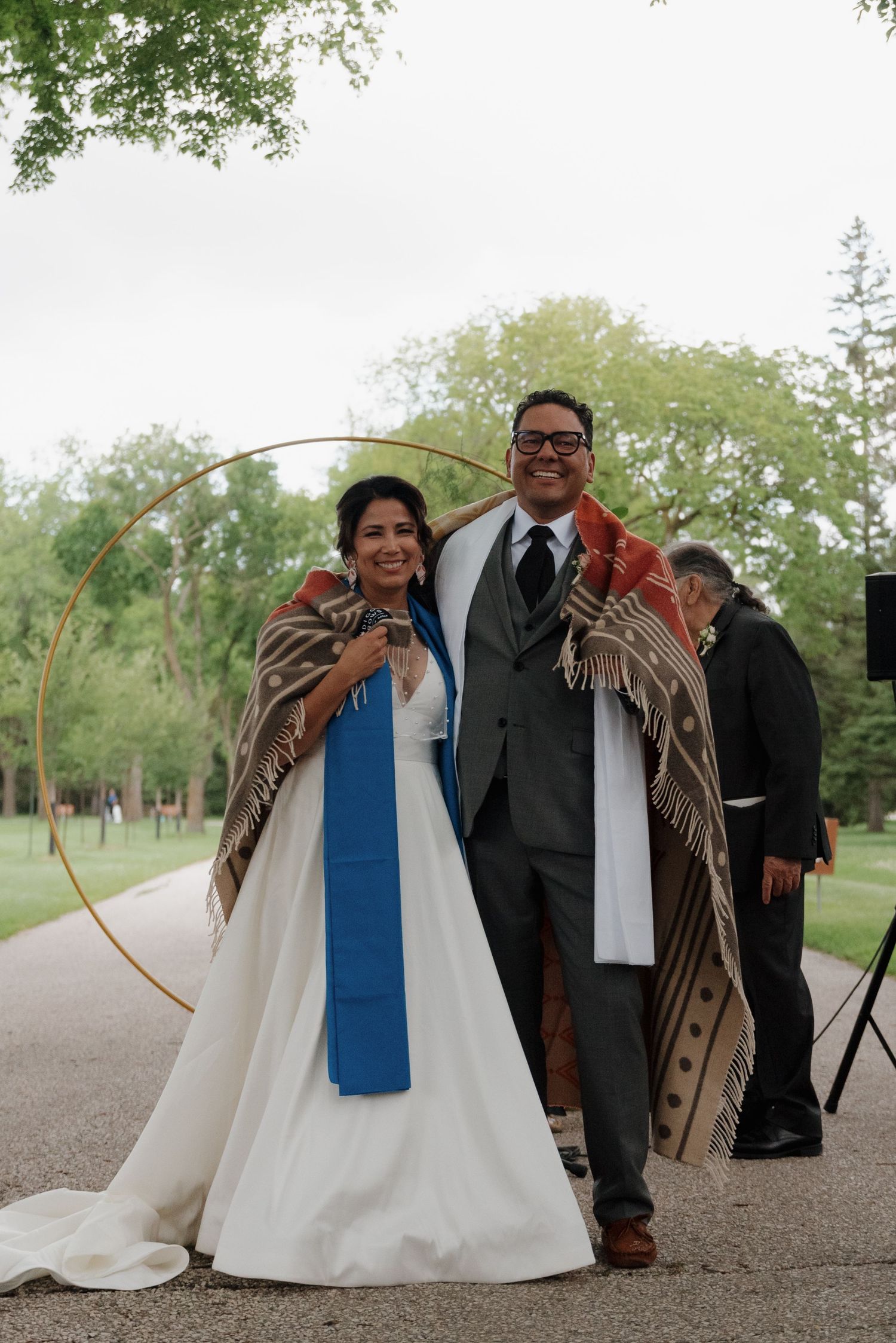Wedding ceremony participants on a gravel path with blue stoles and formal attire.
