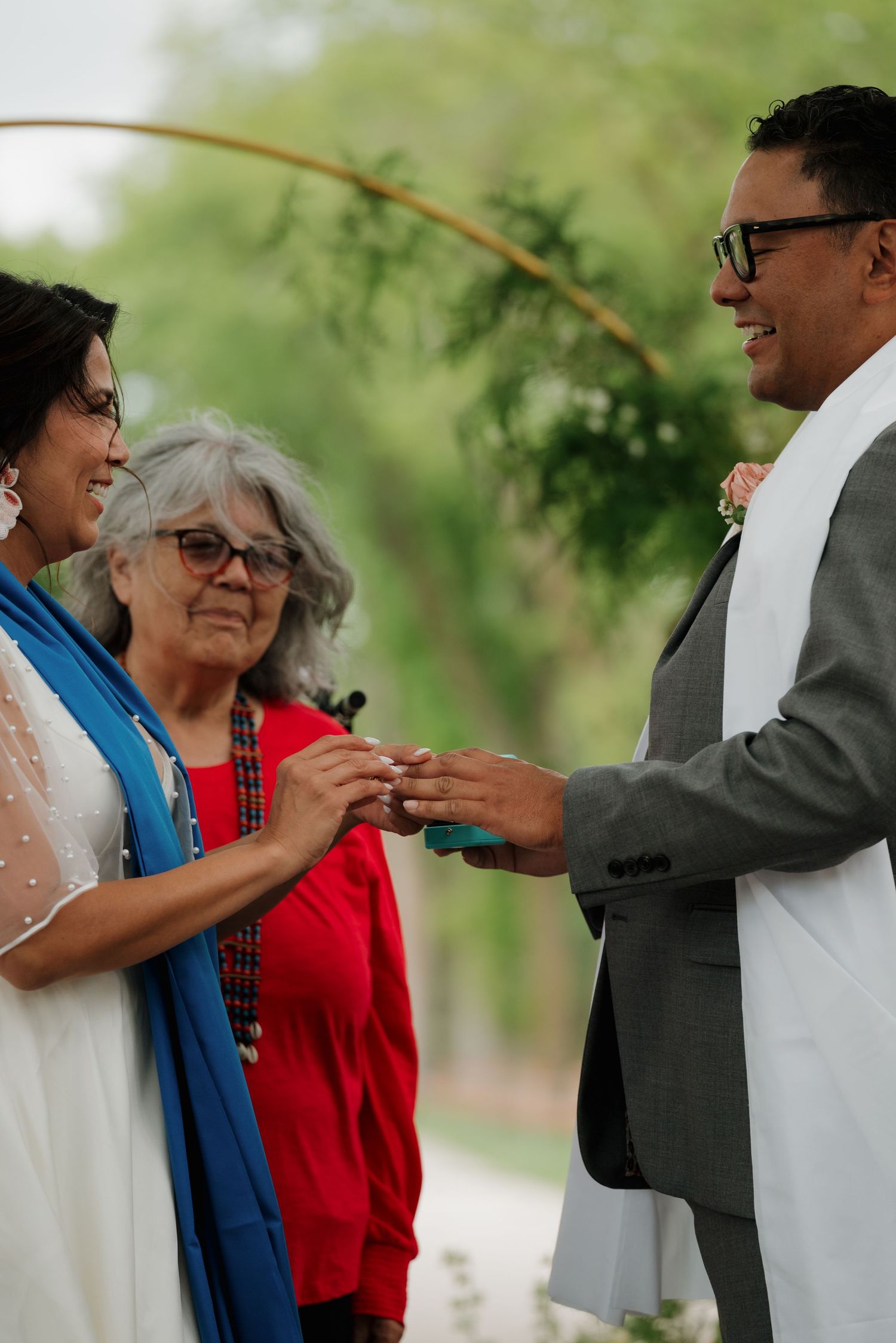 A heartwarming sequence of people embracing during an outdoor celebration beneath shady trees.