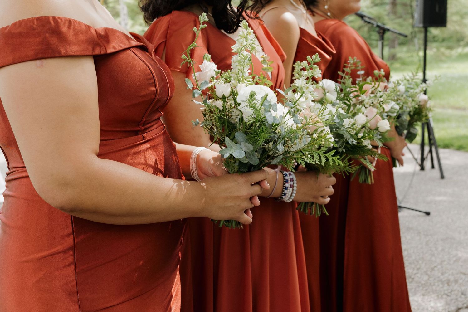 Wedding party members in coral colored dresses holding delicate white floral bouquets.