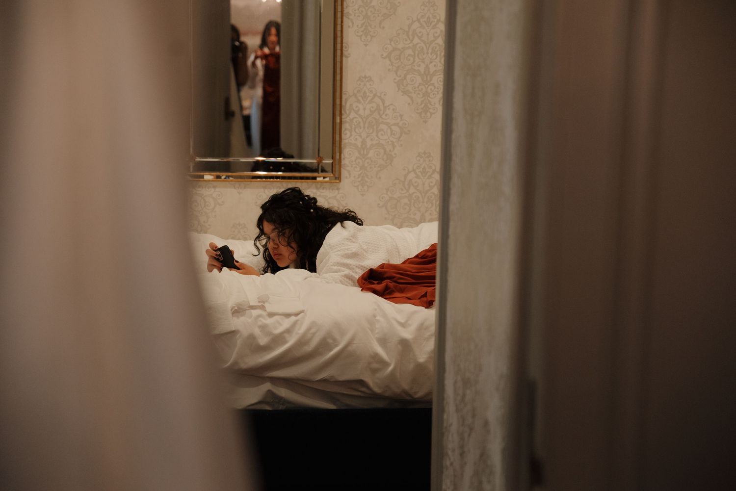 An artistic view through a doorway showing preparation moments in a bedroom.