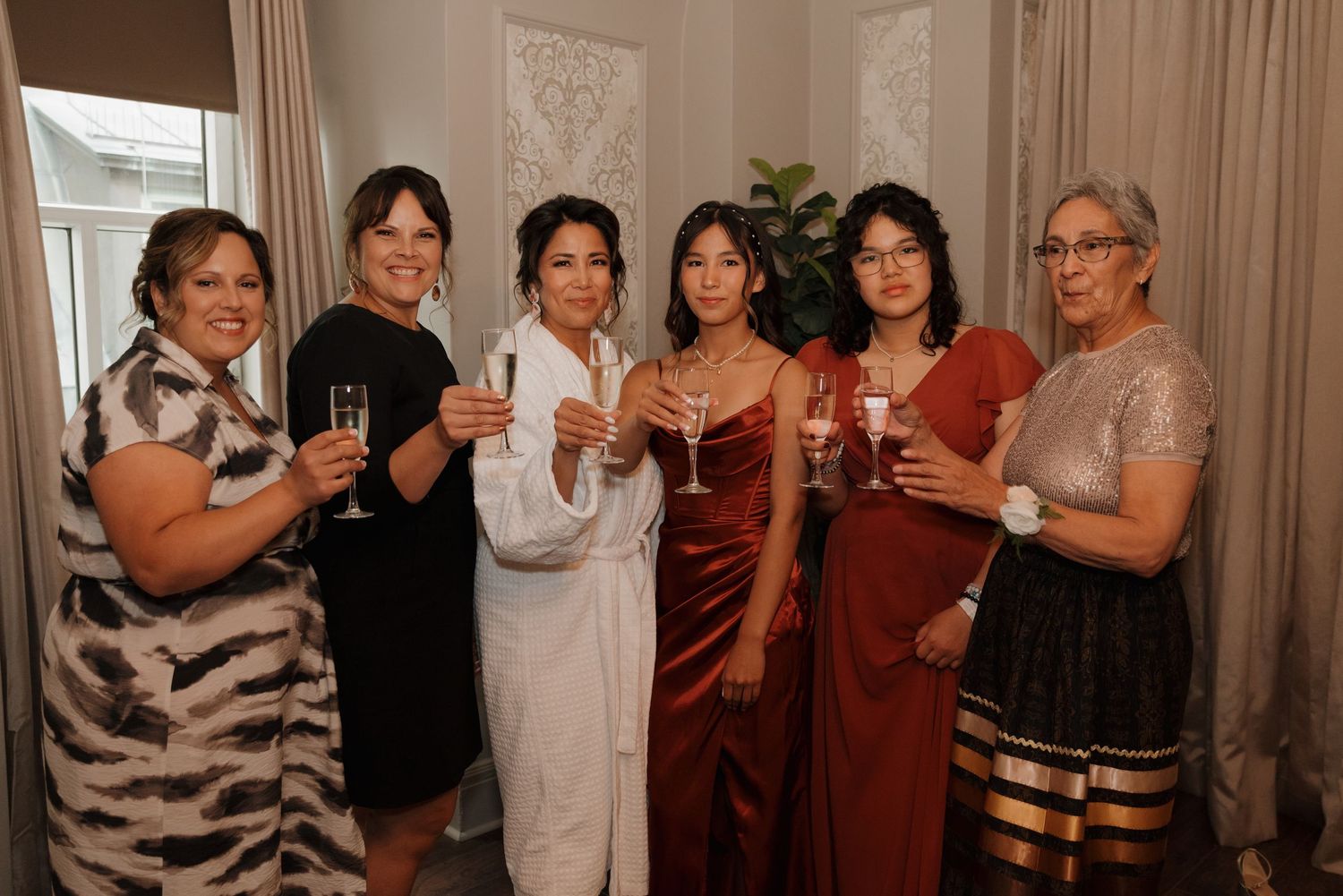 A group in burgundy and white attire pose together during a celebration in an indoor venue.