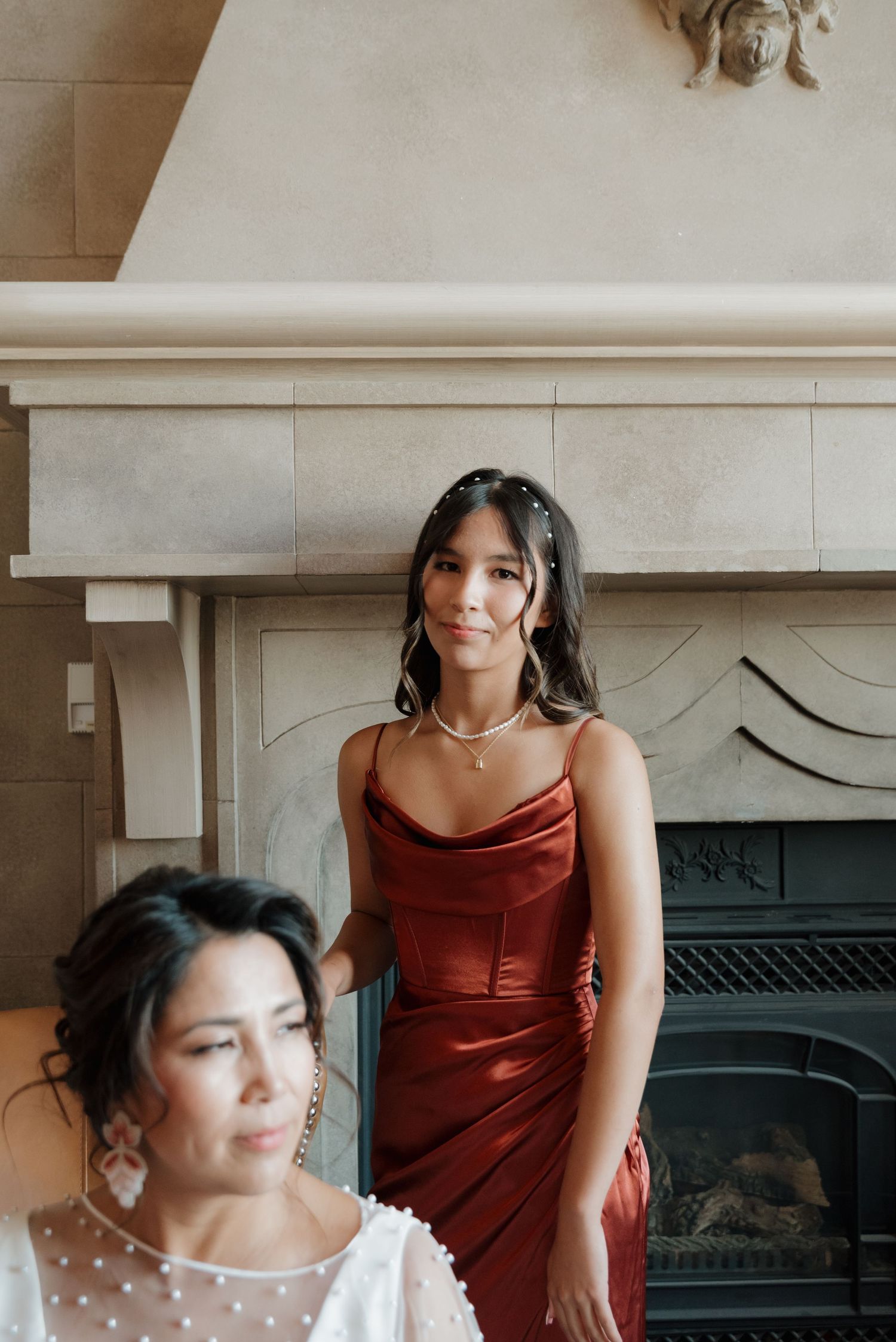 Wedding party members in burgundy dresses getting ready indoors.
