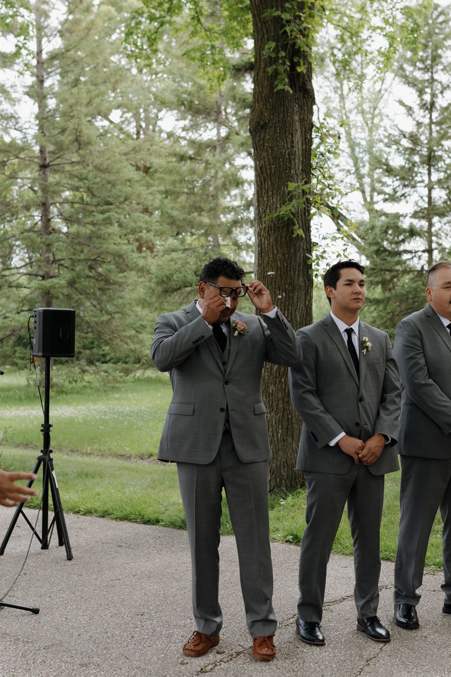 A collage of wedding party groomsmen in gray suits standing outdoors among trees on a paved path.