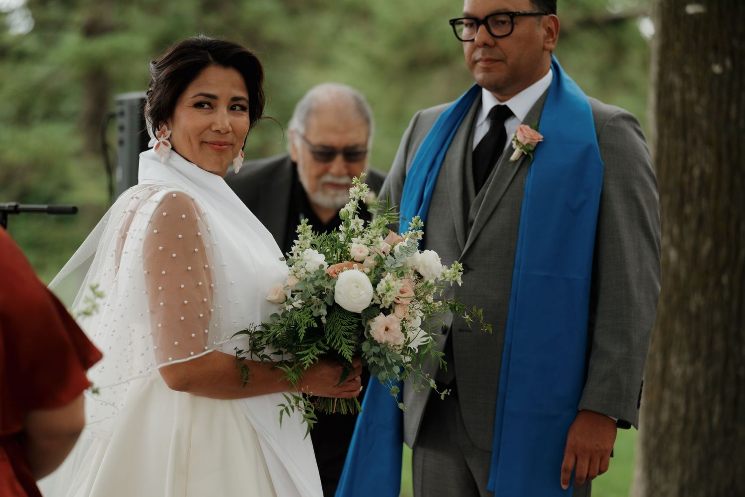 A wedding couple poses together in natural outdoor settings holding delicate floral bouquets.