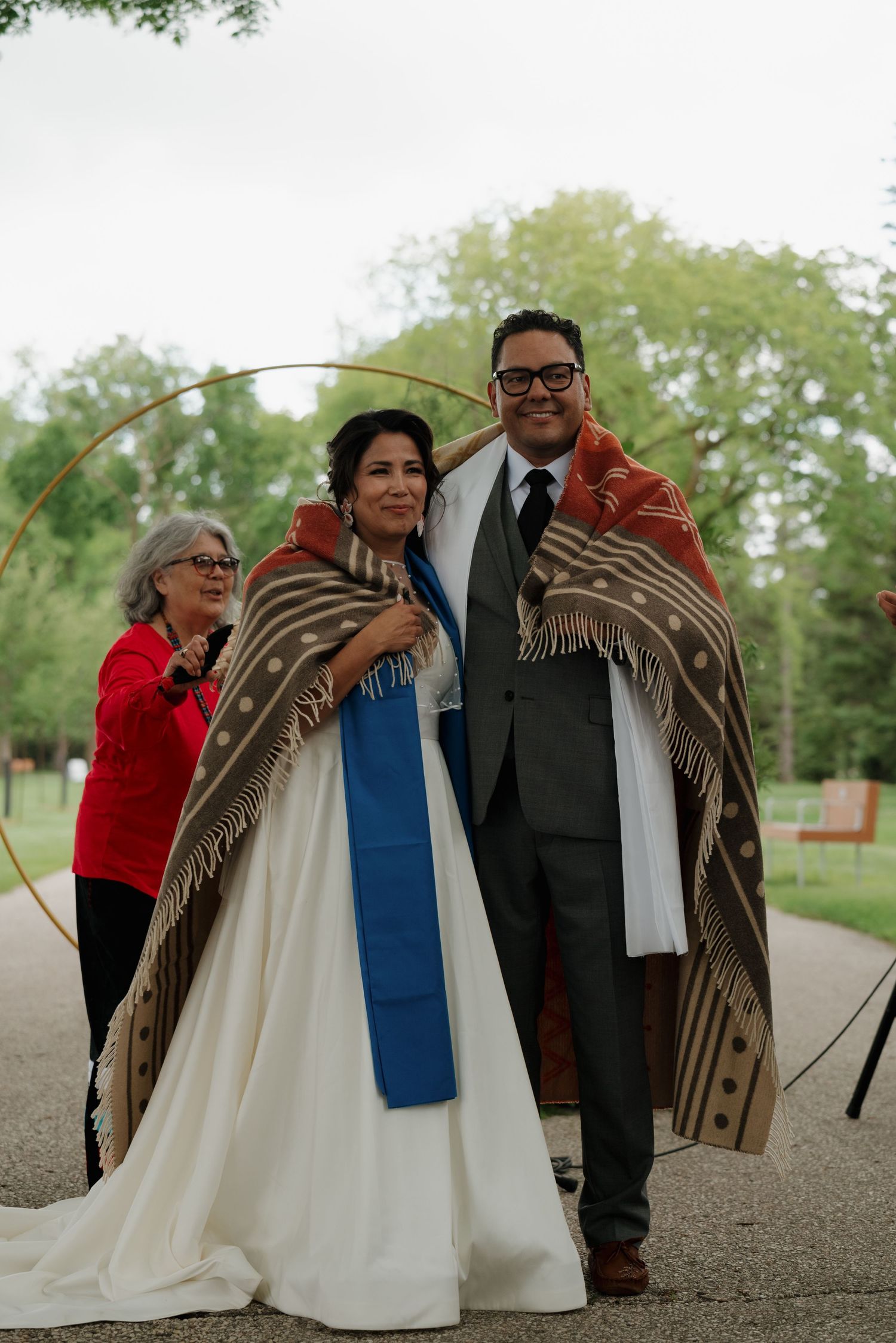 Artistic sequence of wedding guests sharing a brown blanket outdoors.
