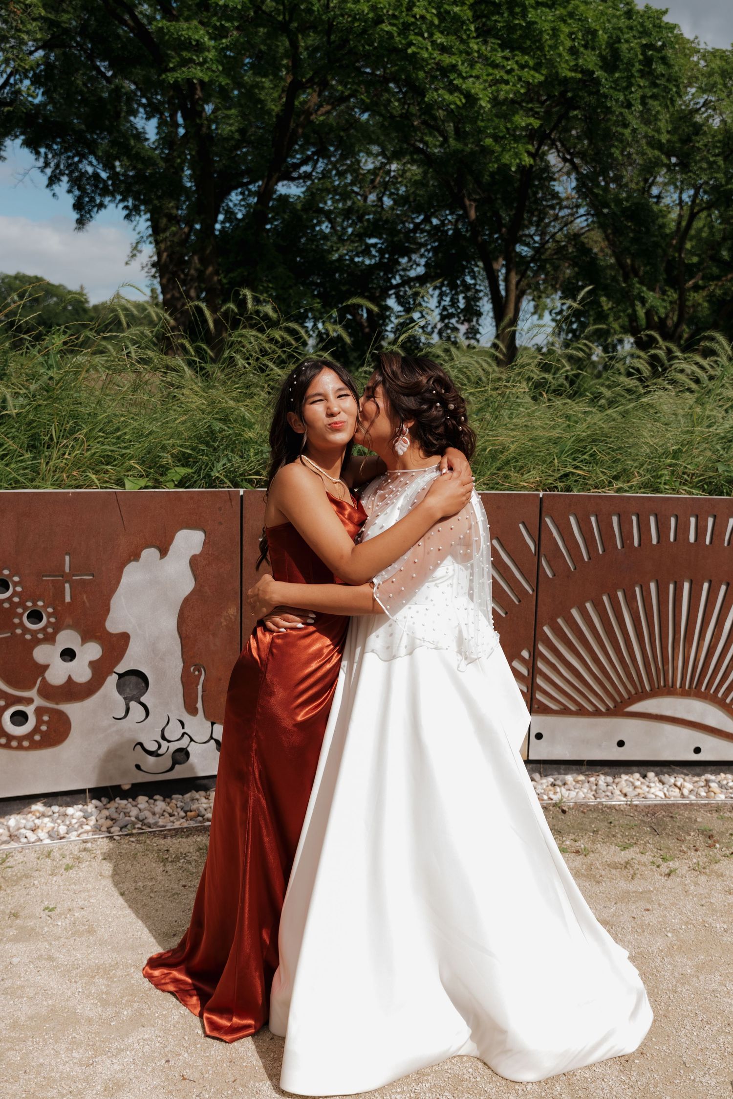 Wedding couple sharing tender moments against a rustic metal wall backdrop in warm sunlight.