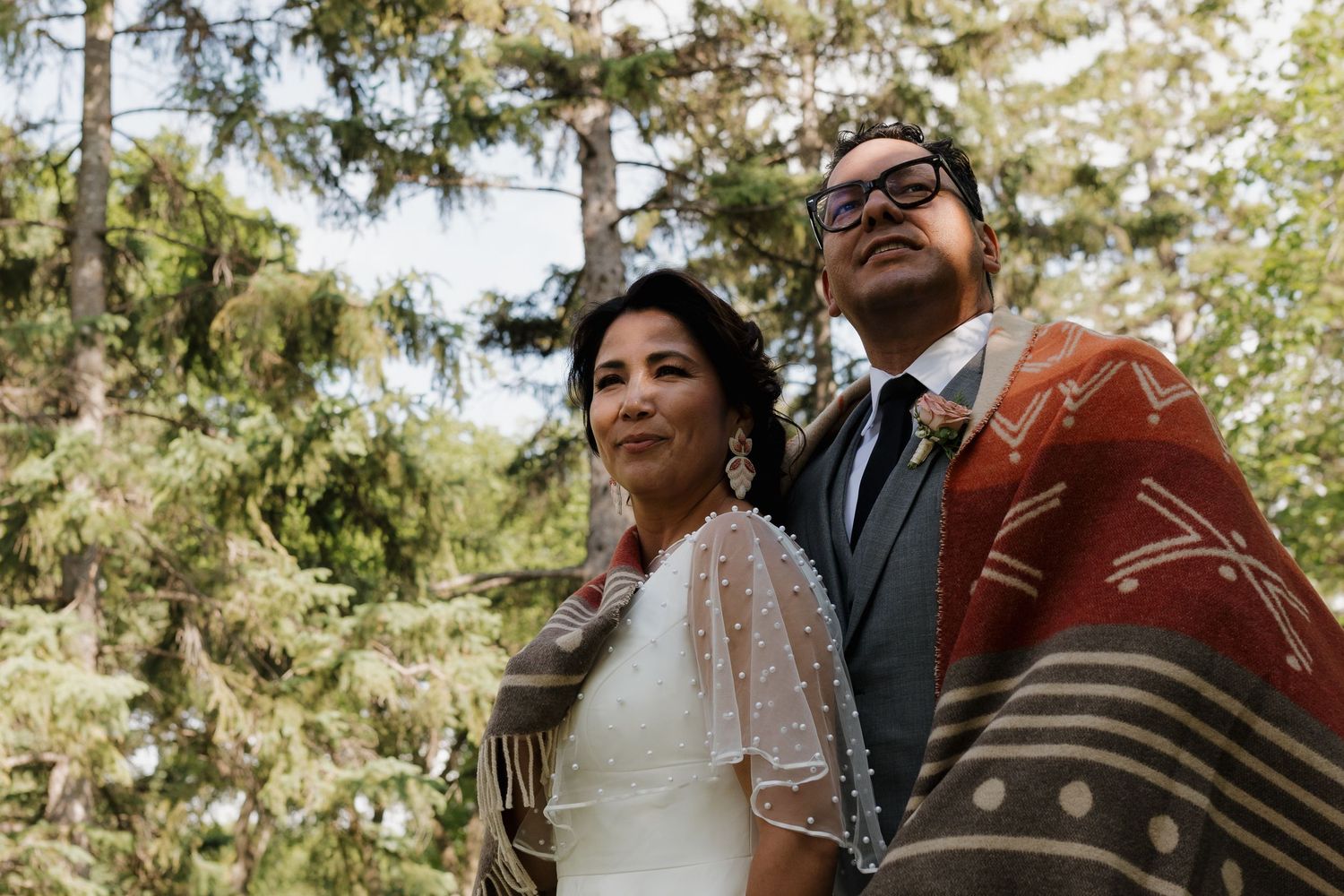 A couple shares intimate moments during an outdoor wedding photoshoot among blooming trees and natural scenery.