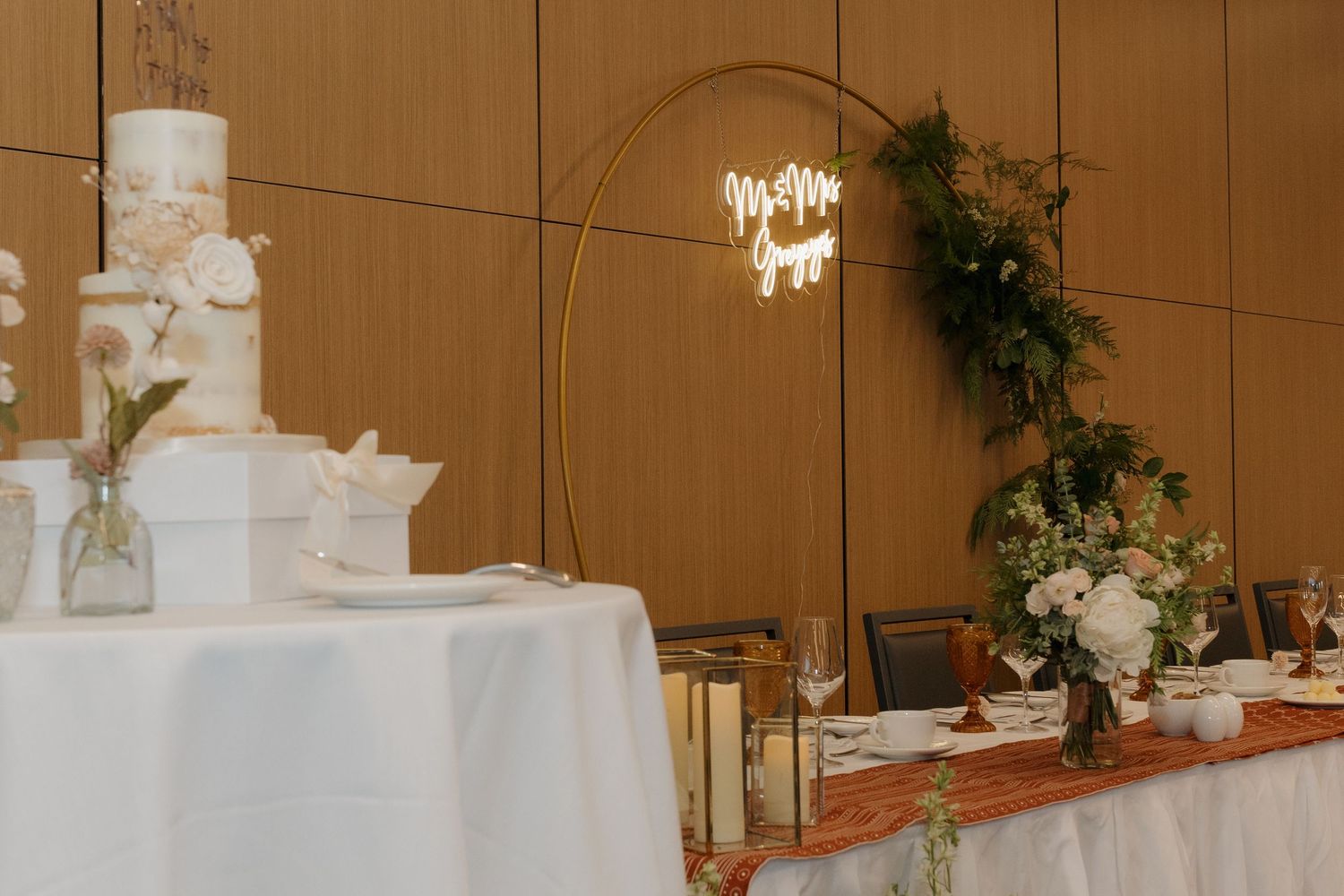 Elegant ballroom reception venue with white tablecloths, floral arrangements and soft amber lighting from chandeliers.